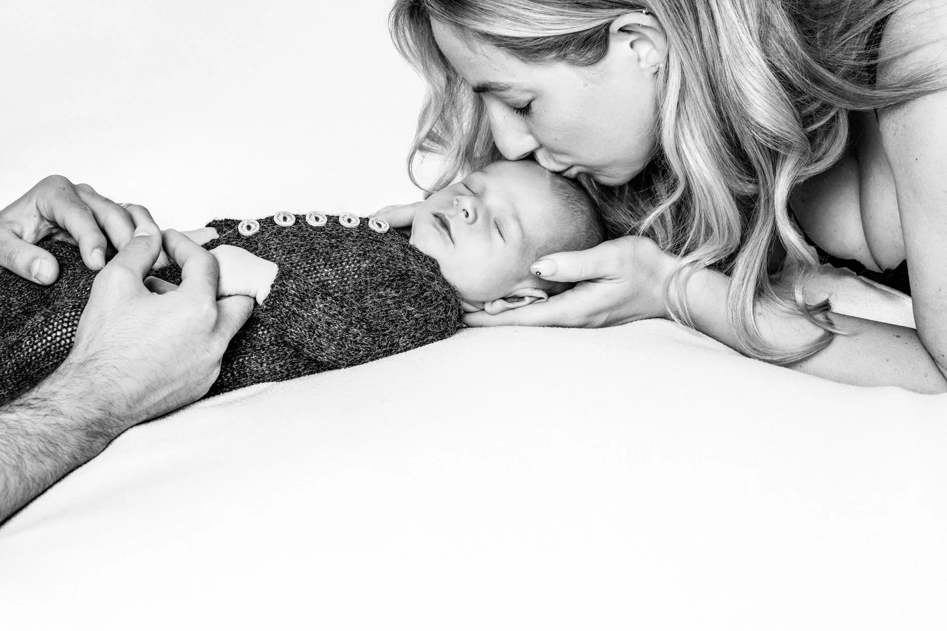 Tender black and white newborn photography session showing parents loving on their sleeping baby at a studio in Seattle, WA.