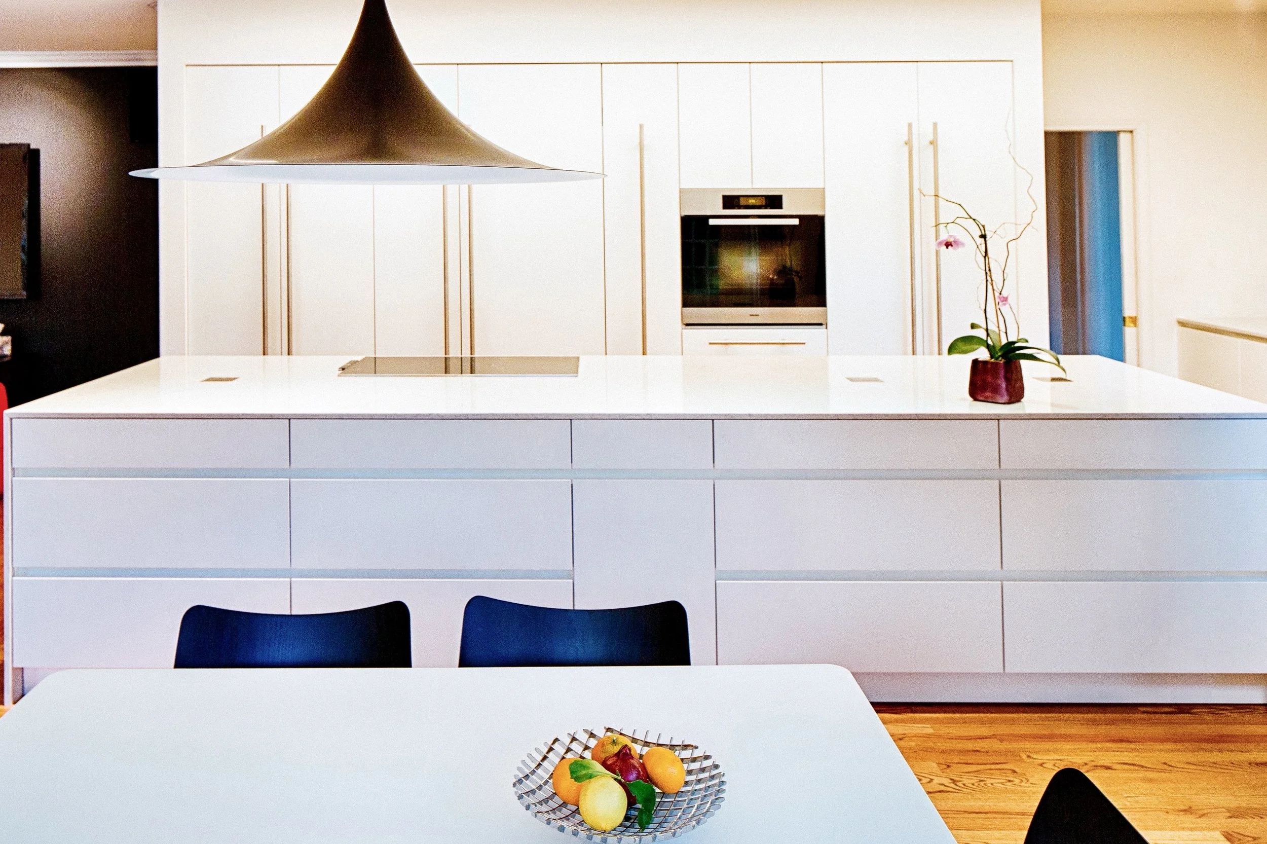 White contemporary kitchen with sculptural pendant and handleless cabinetry