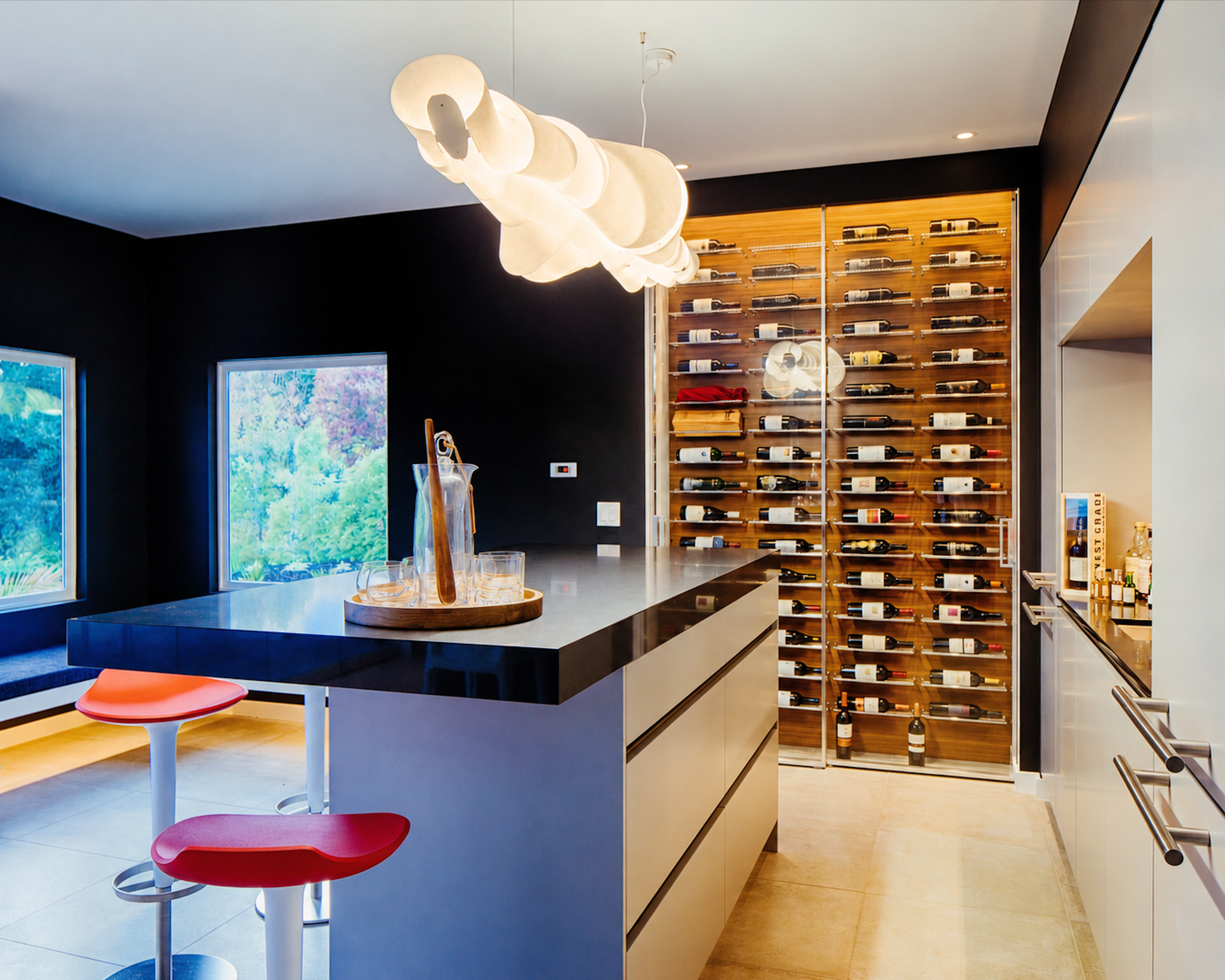 Custom bar and wine room with illuminated bottle storage and sculptural pendant lighting