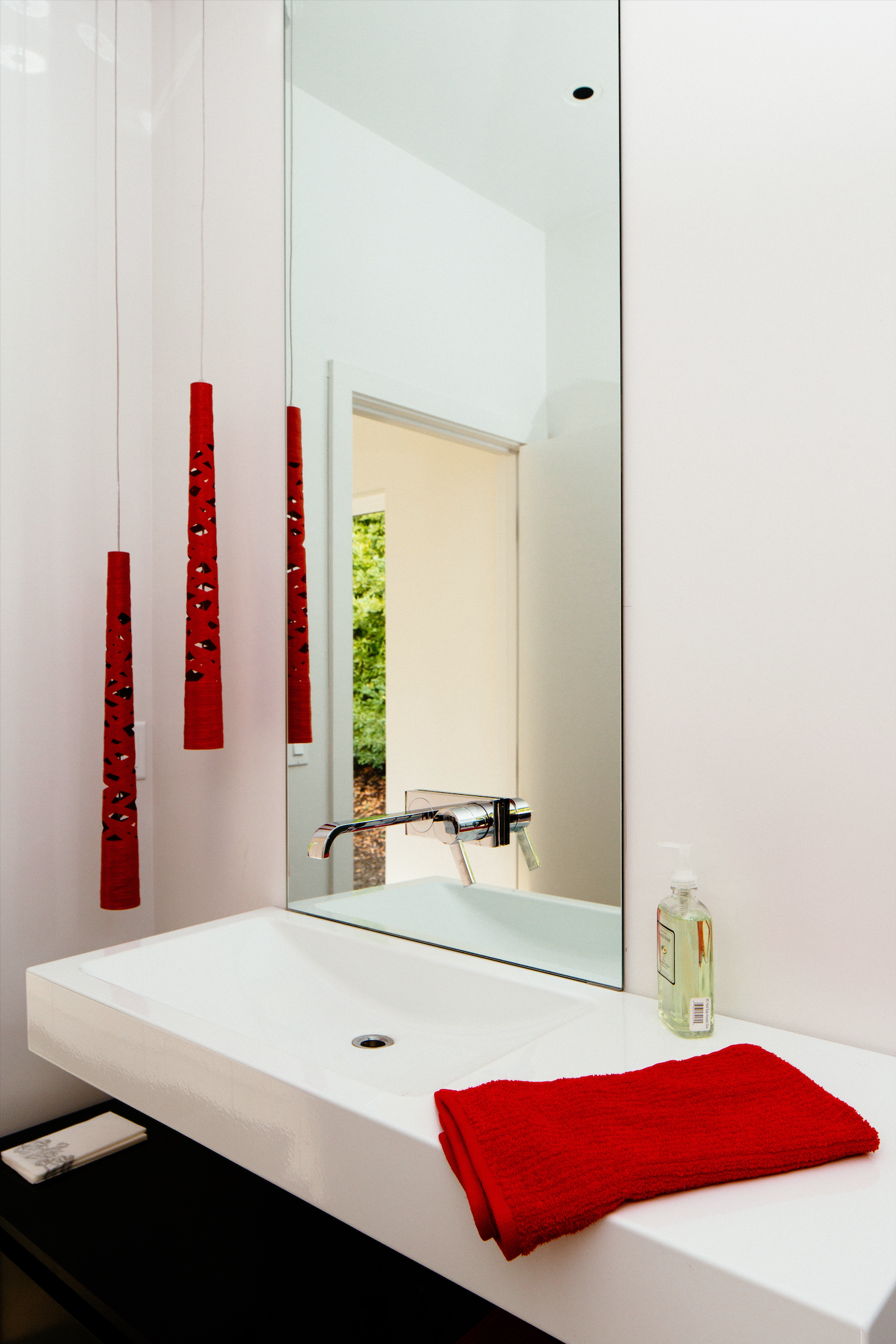 Powder room with floating white vanity, full-height mirror, and red decorative accents