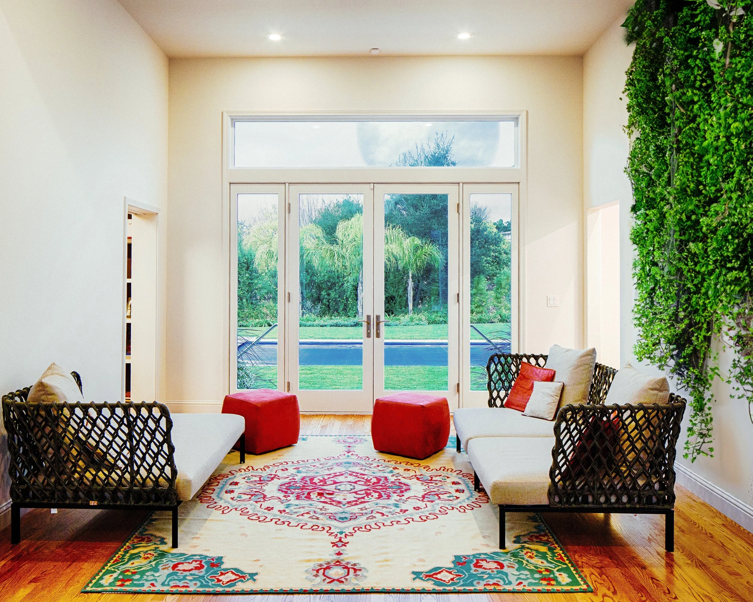 Foyer with indoor green wall, colorful seating, and glass doors overlooking the pool