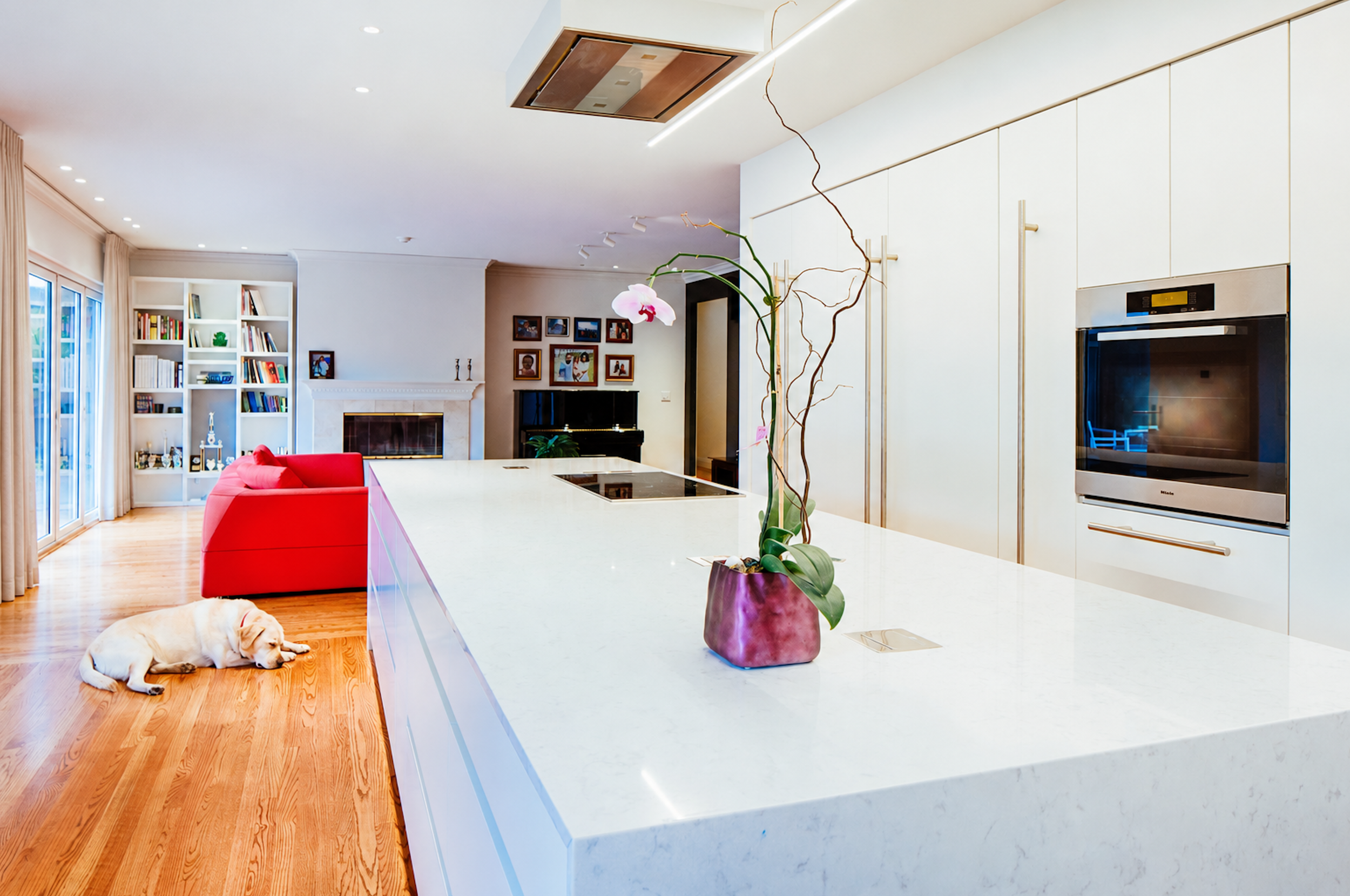 White waterfall island and full-height cabinetry connecting the kitchen to the living area