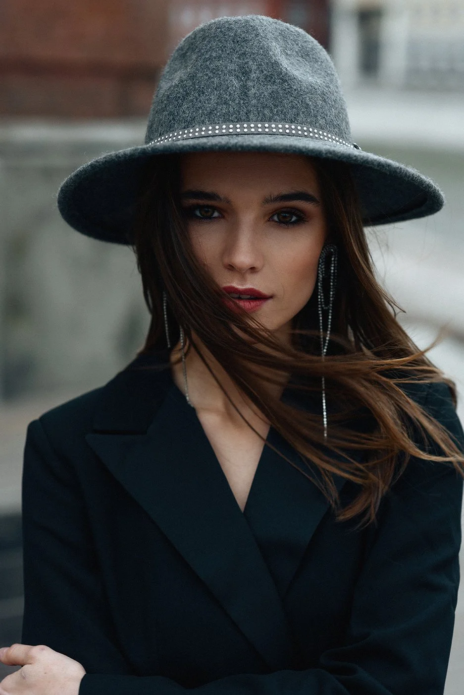 Editorial portrait of a woman in a black blazer and grey hat