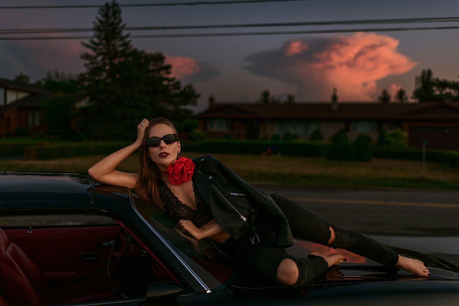 A portrait beside a car under a vivid evening sky