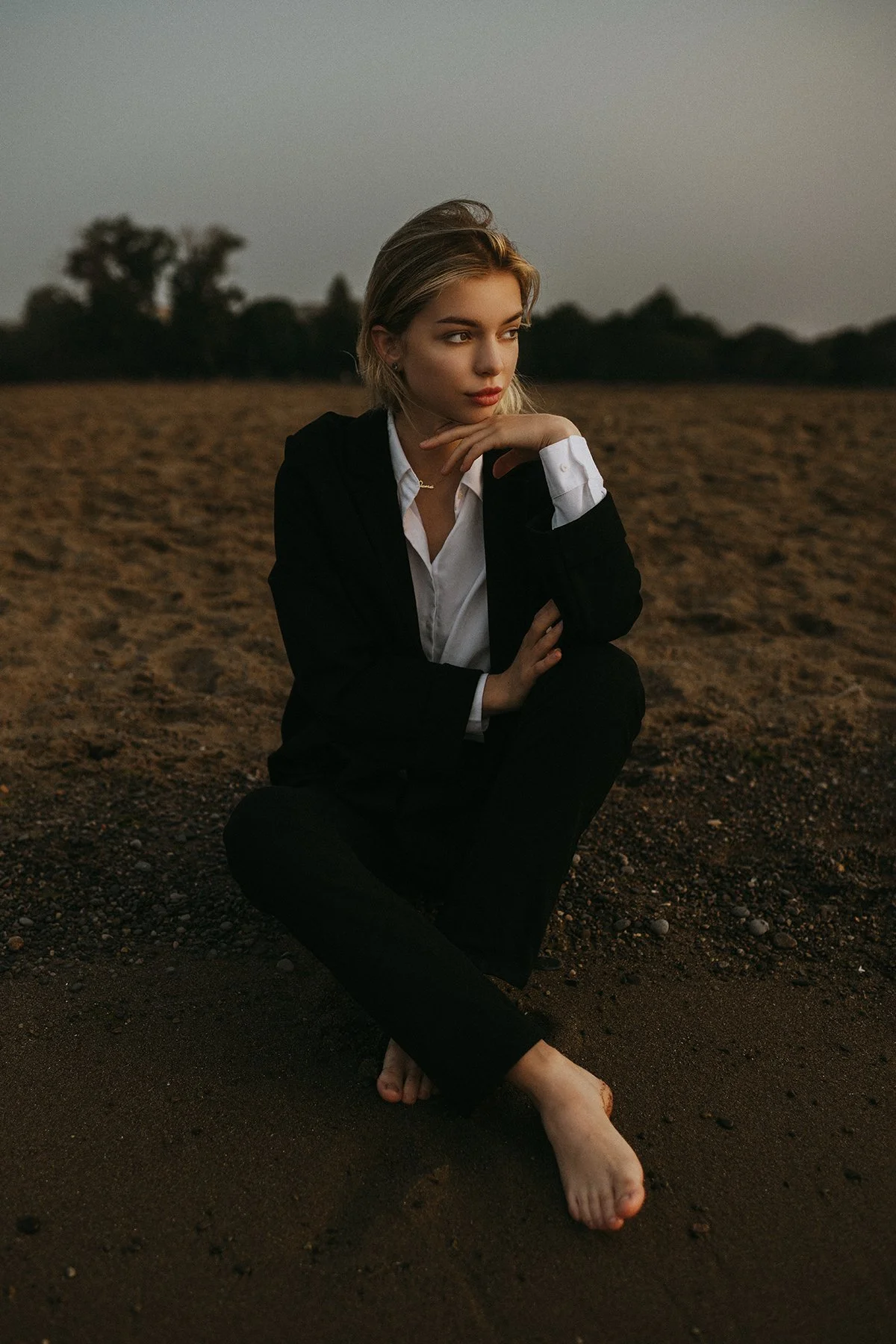 A seated portrait in a dark suit on open ground