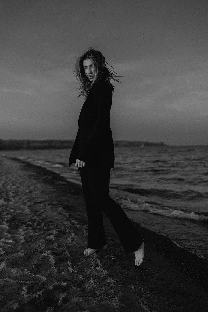 A black-and-white portrait at the edge of the water