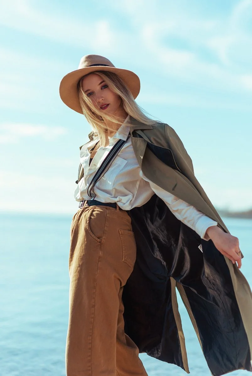 A lakeside portrait with a hat and flowing coat