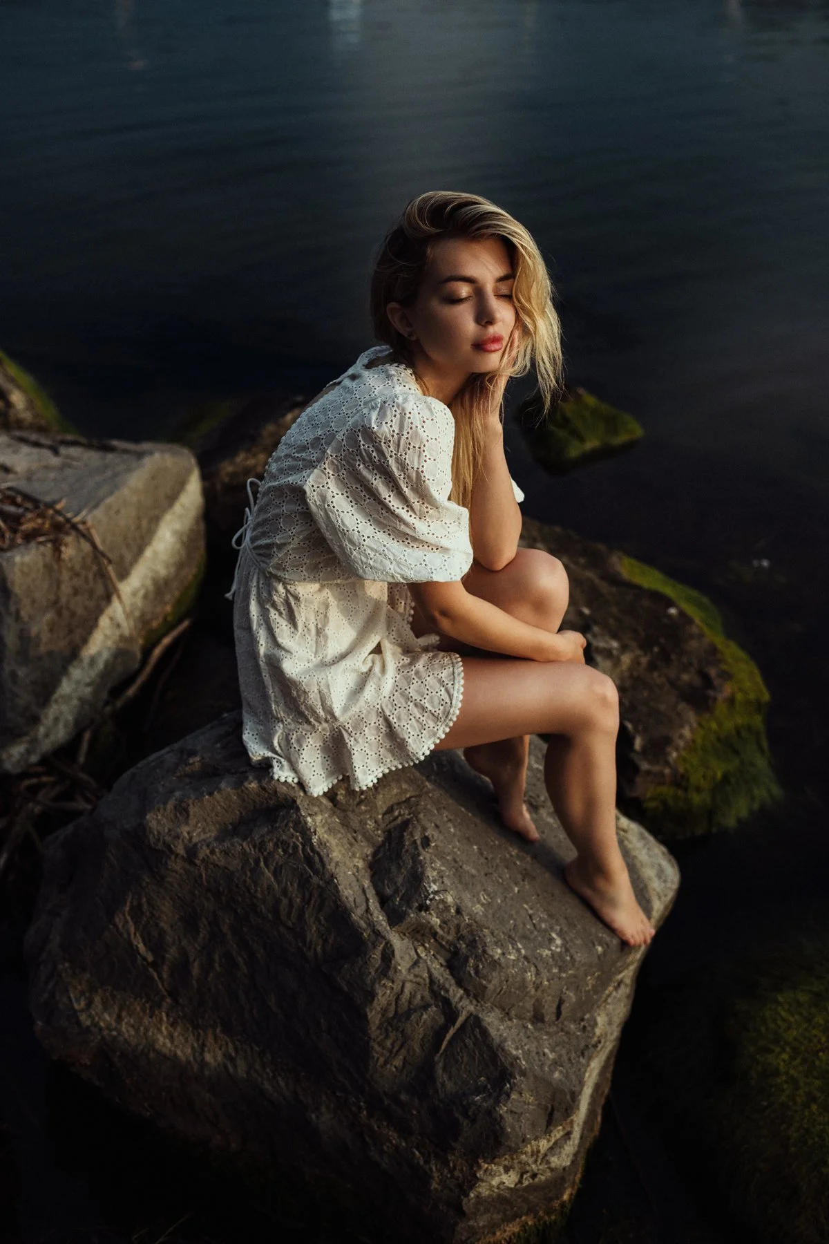 A quiet portrait seated on rocks by the water