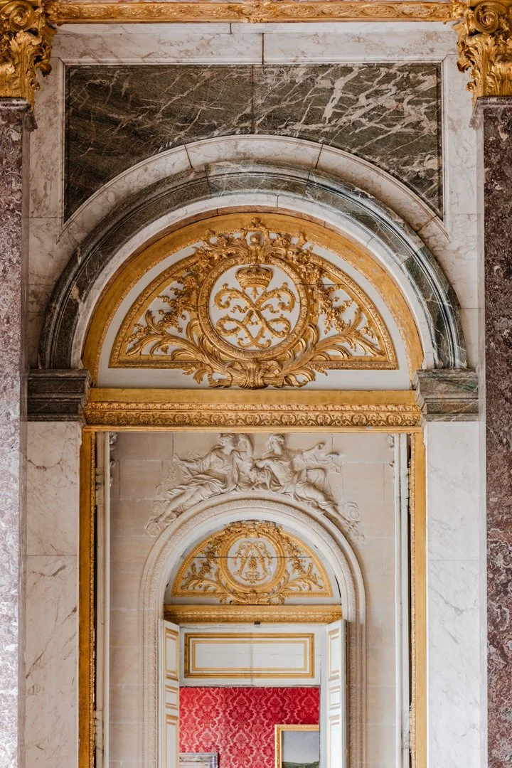 View of an ornate, gold-accented architectural detail in a historic building, featuring marble, gilded carvings, and decorative reliefs.