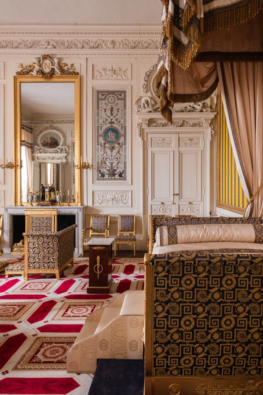 Interior of a luxurious, ornate room with antique furnishings, gold accents, patterned drapes, and elaborate wall decor