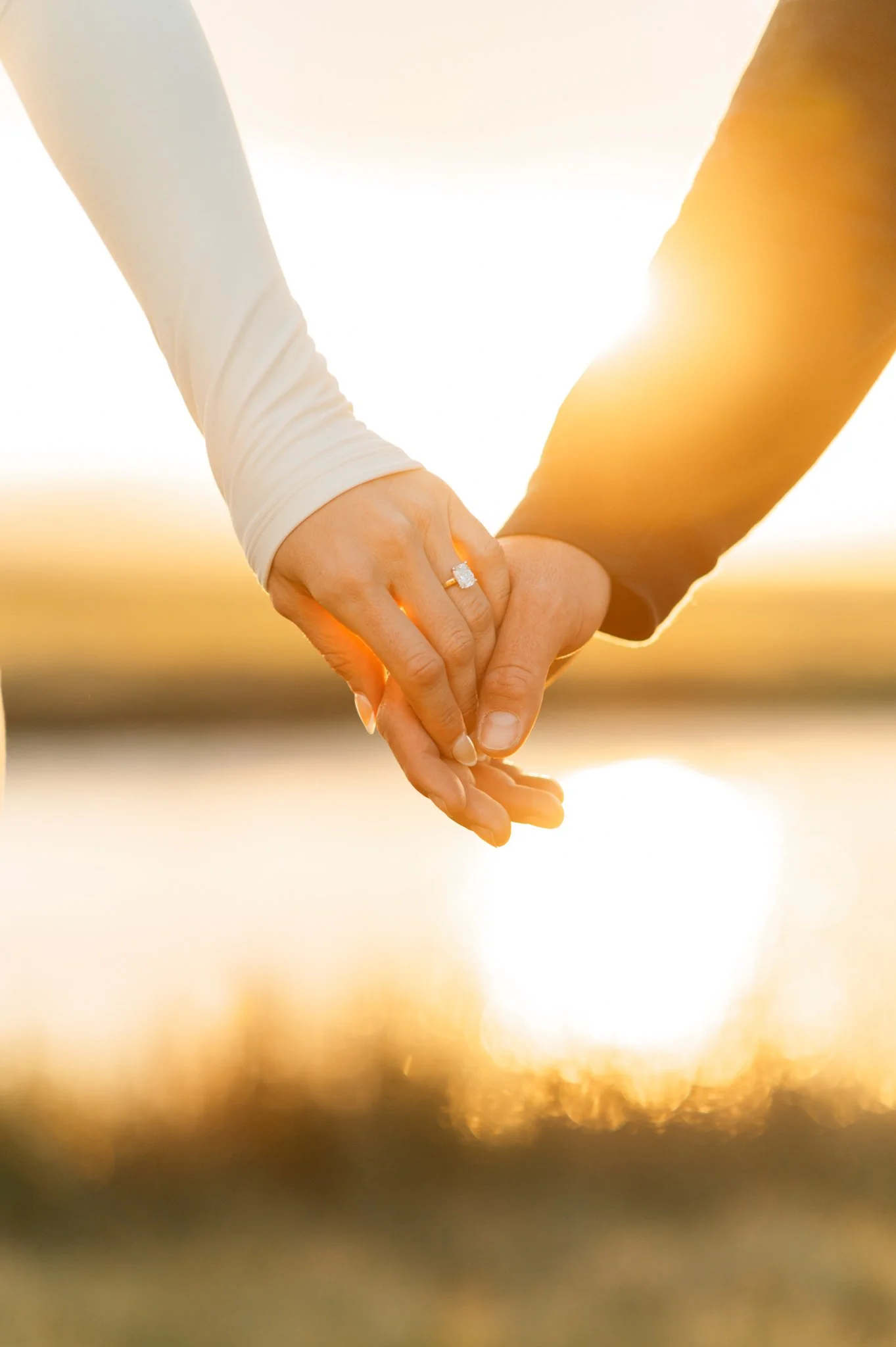 man and womens hands in the sunset next to the owens river with a big engagement ring