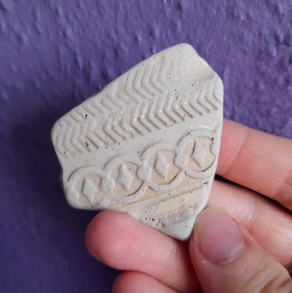 Piece of white pottery with various patterns, age unknown.