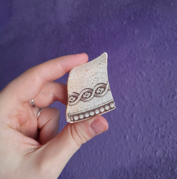 Pottery shard with brown pattern, age unknown.