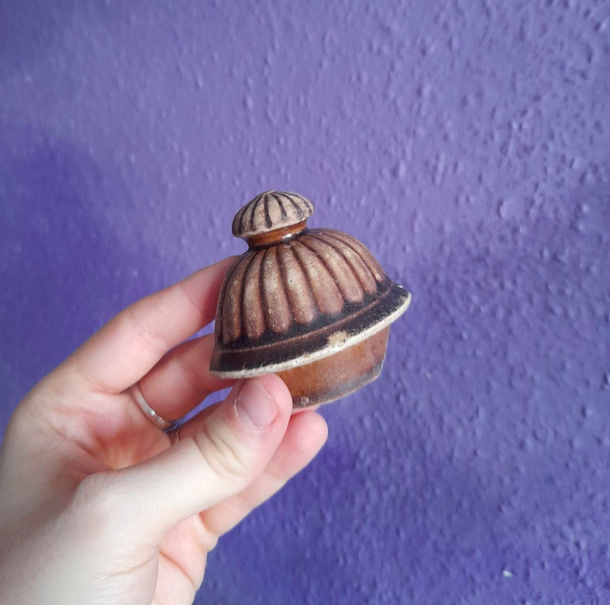 Part of a ribbed, glazed pottery lid, age unknown.