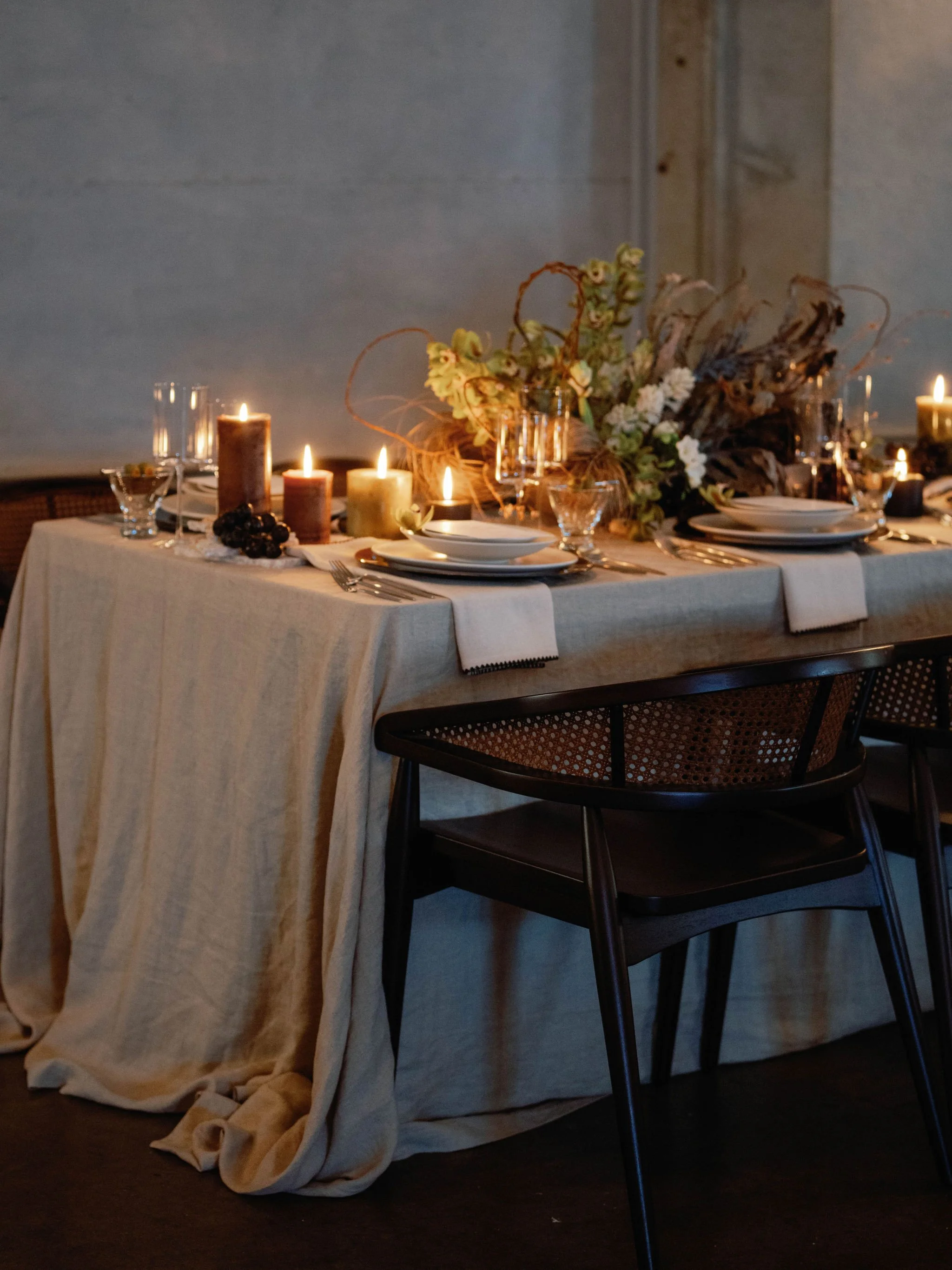 Decorative dining table set with candles, plates, glasses, and a floral centerpiece
