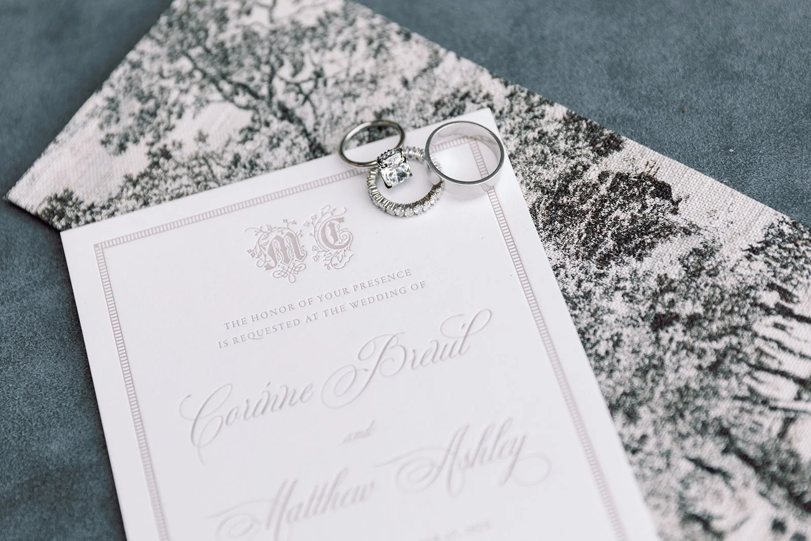 Wedding invitation with two rings placed on top, a snow-covered landscape photo underneath, and a gray surface background.