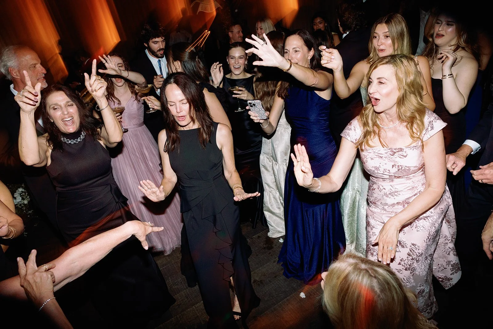 People dancing and celebrating at a party or wedding reception in elegant attire.