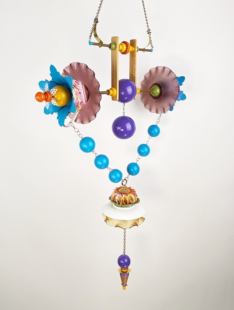 A custom made hanging sculpture that cocntains a series of blue spheres, metal peices, and hangs in the shape of a diamond