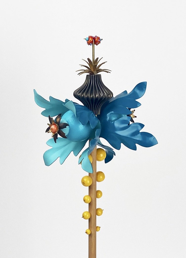 a detail of the "sky" sculpture made up of wood, beads, and metal resembling two blue flowers