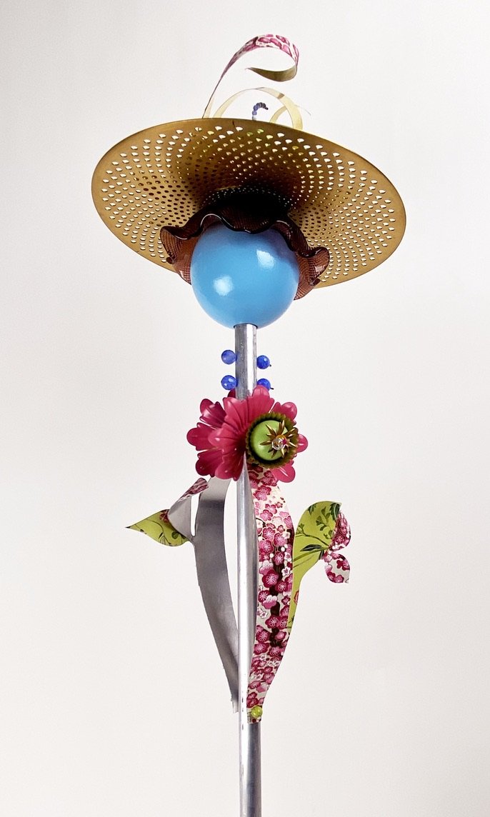 A detailed view of the top of the "hat" sculpture made of Wood ball and top spiral, cymbal , lamp parts, glass bowl, china plate beads, sheet metal, paper, aluminum tube, wire and jewelry findings.