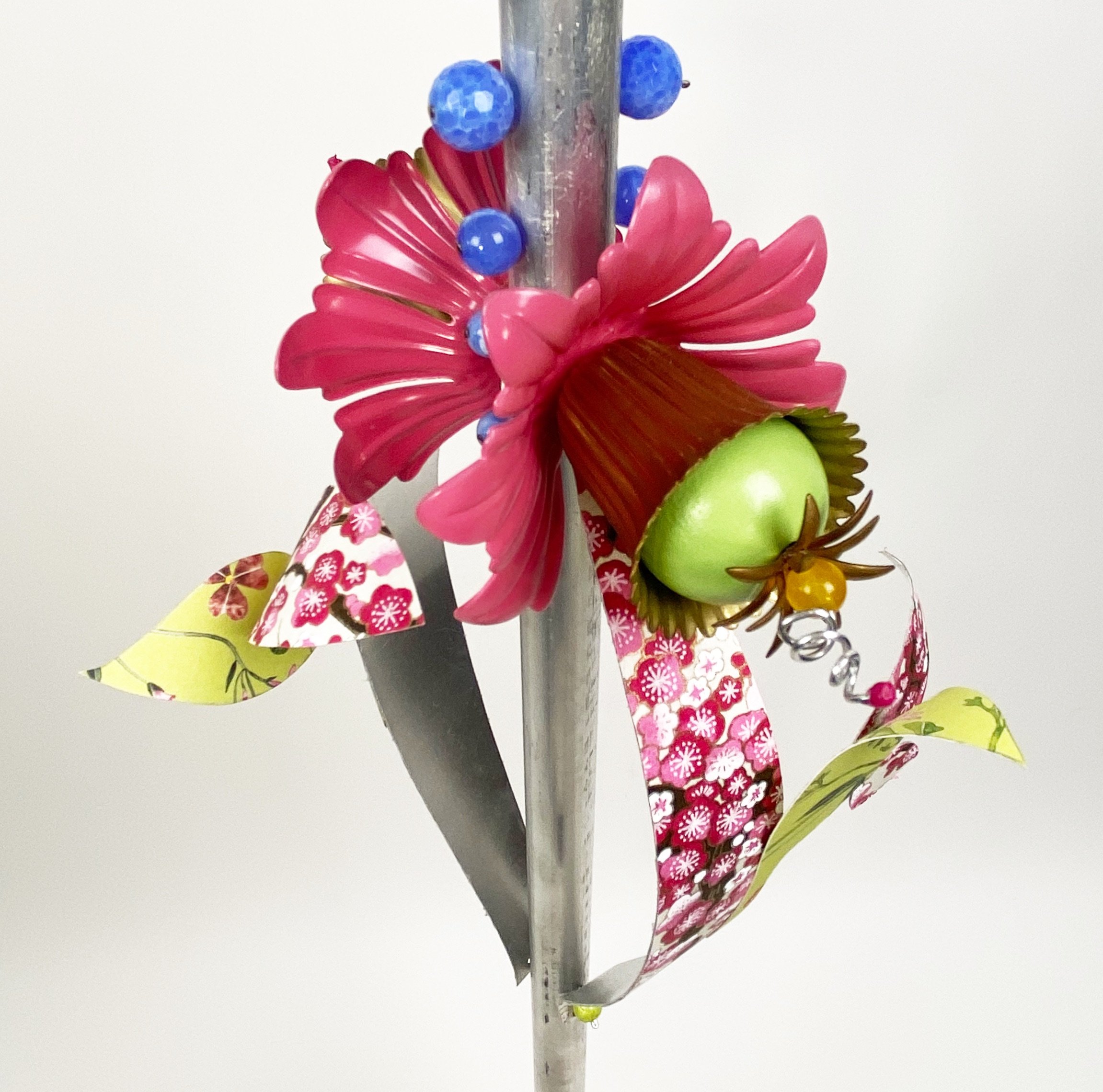 a detailed view of the middle of the "hat" sculputre that looks like two pink flowers surrounded by patterns, spheres, and blue and green