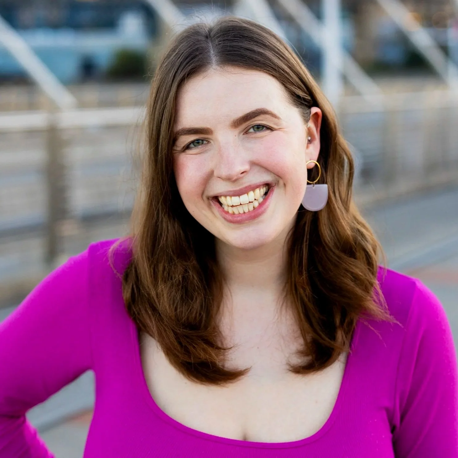 Brunette woman in a pink dress smiling at the camera
