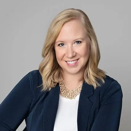 Blonde woman with blue blazer and white shirt, smiling at the camera