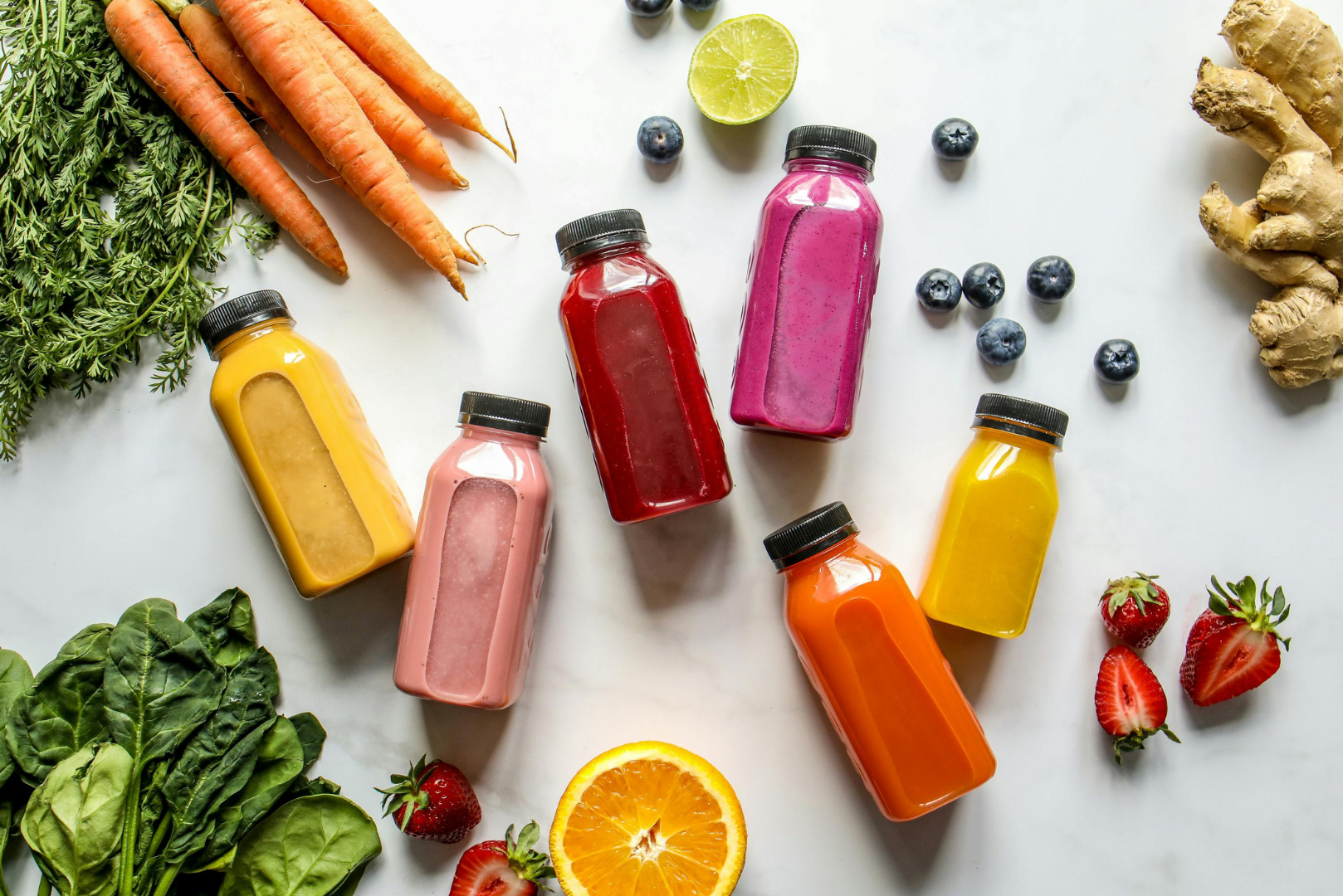 Colorful juice bottles and fresh produce on a white background, representing popular wellness trends and juice cleanses that may not support gut health for everyone