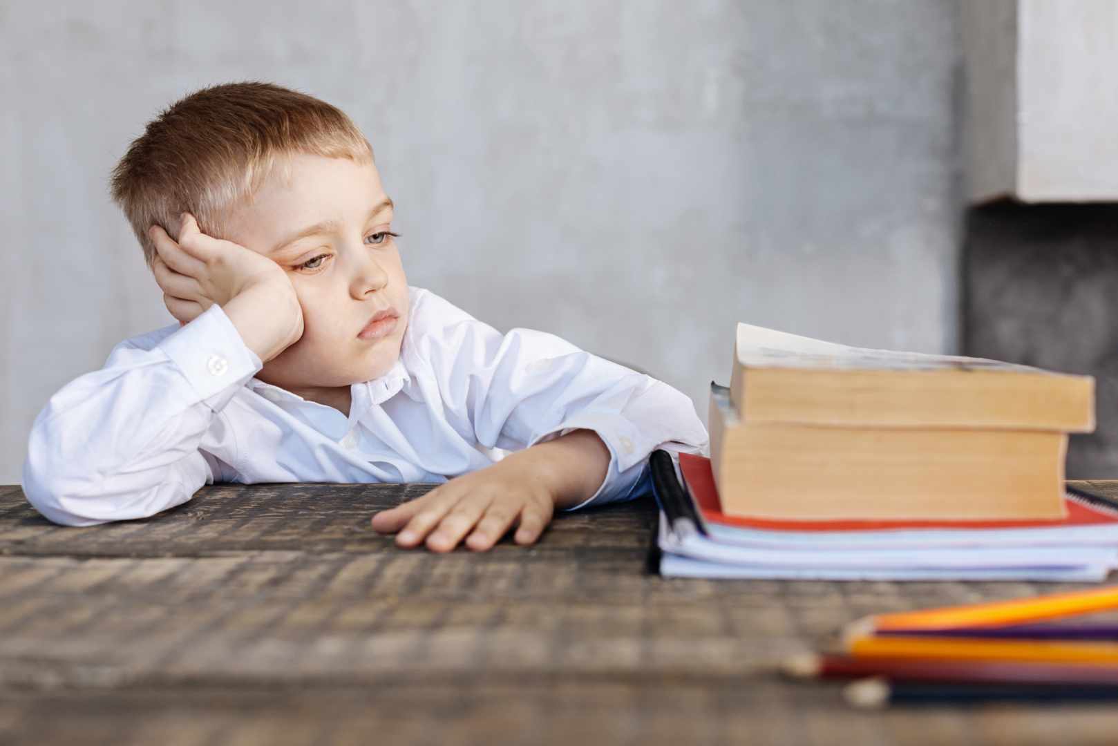 Tired child sitting at a table with school books, representing child fatigue and low energy in Sarasota.