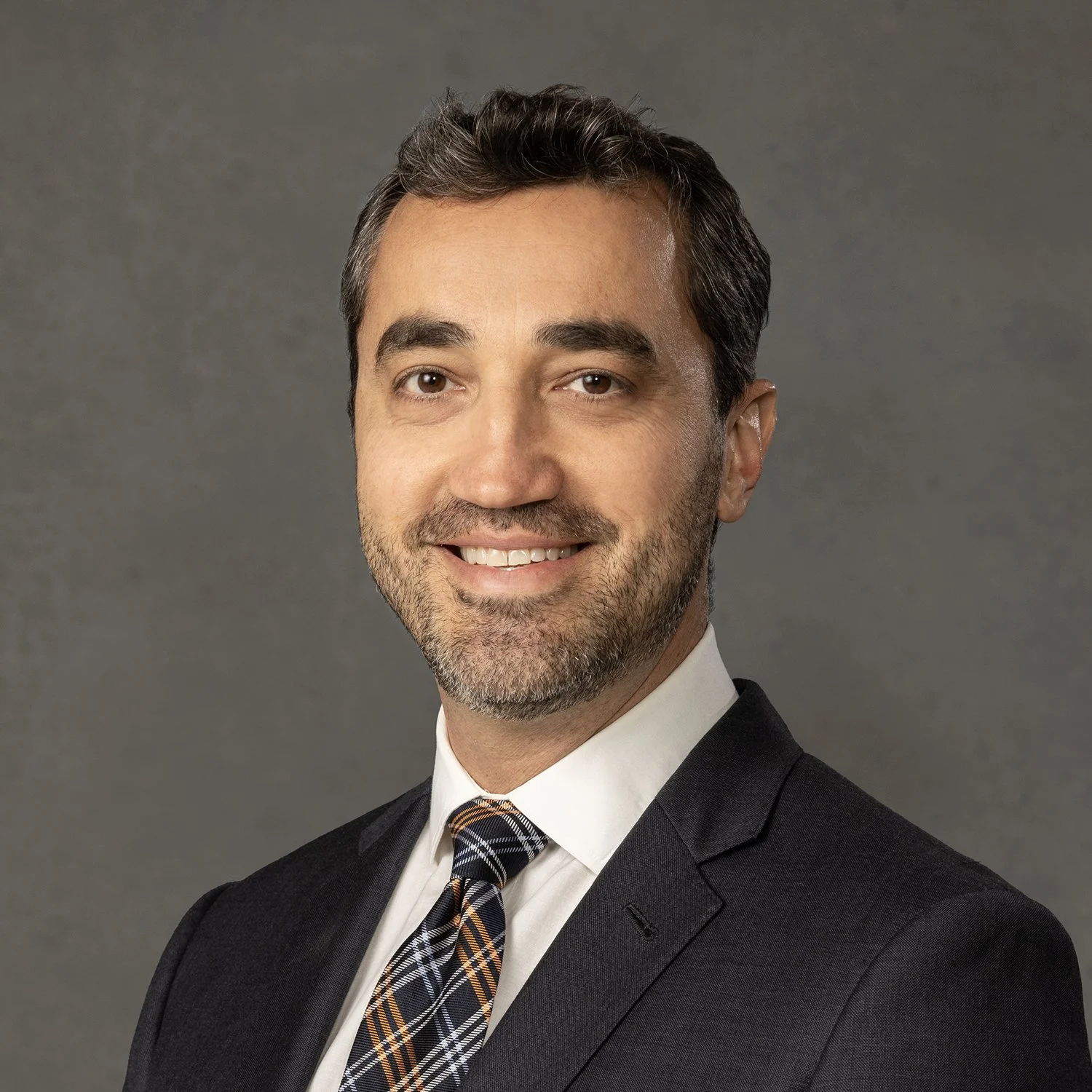 Smiling man in a suit and tie against a plain background