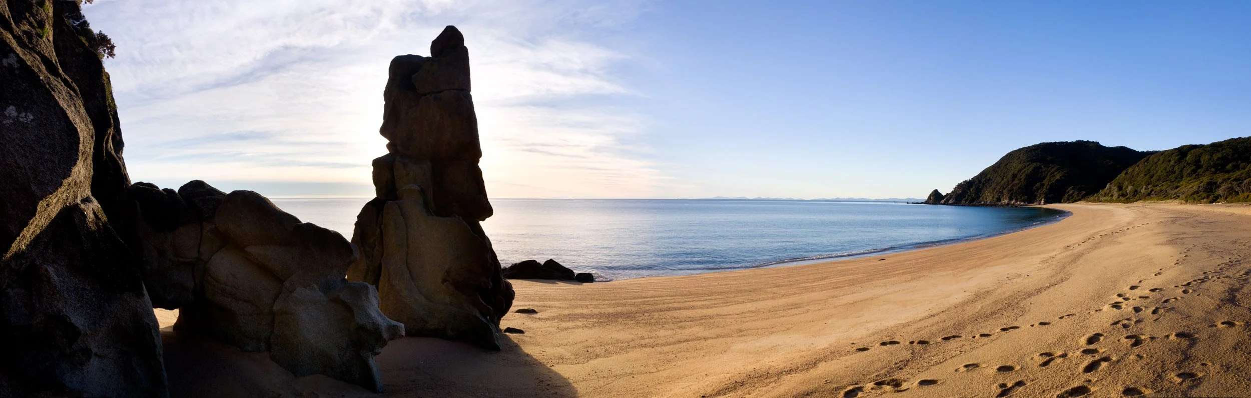 Granite Rock formations and footsteps on the beach at Anapai Bay.