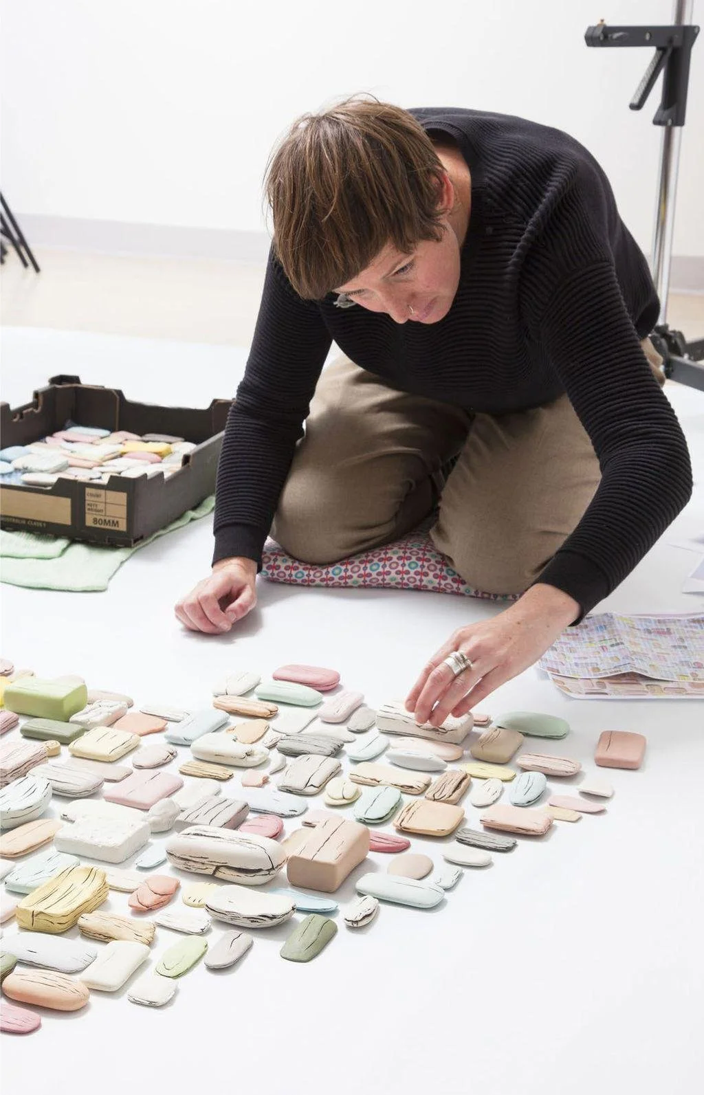 Person arranging pastel-colored ceramic pieces on a white surface