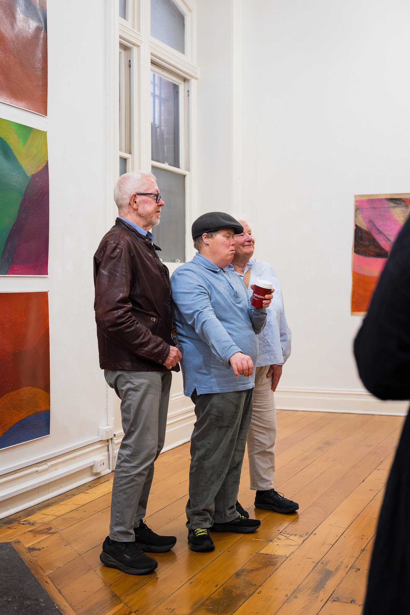 People and the artist observing drawings at an exhibition