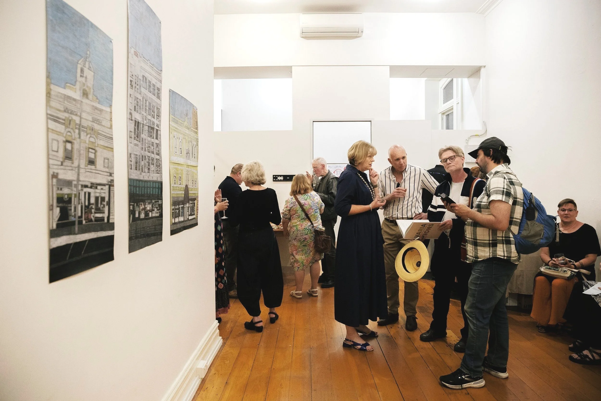 People at a gallery event with art on the walls.