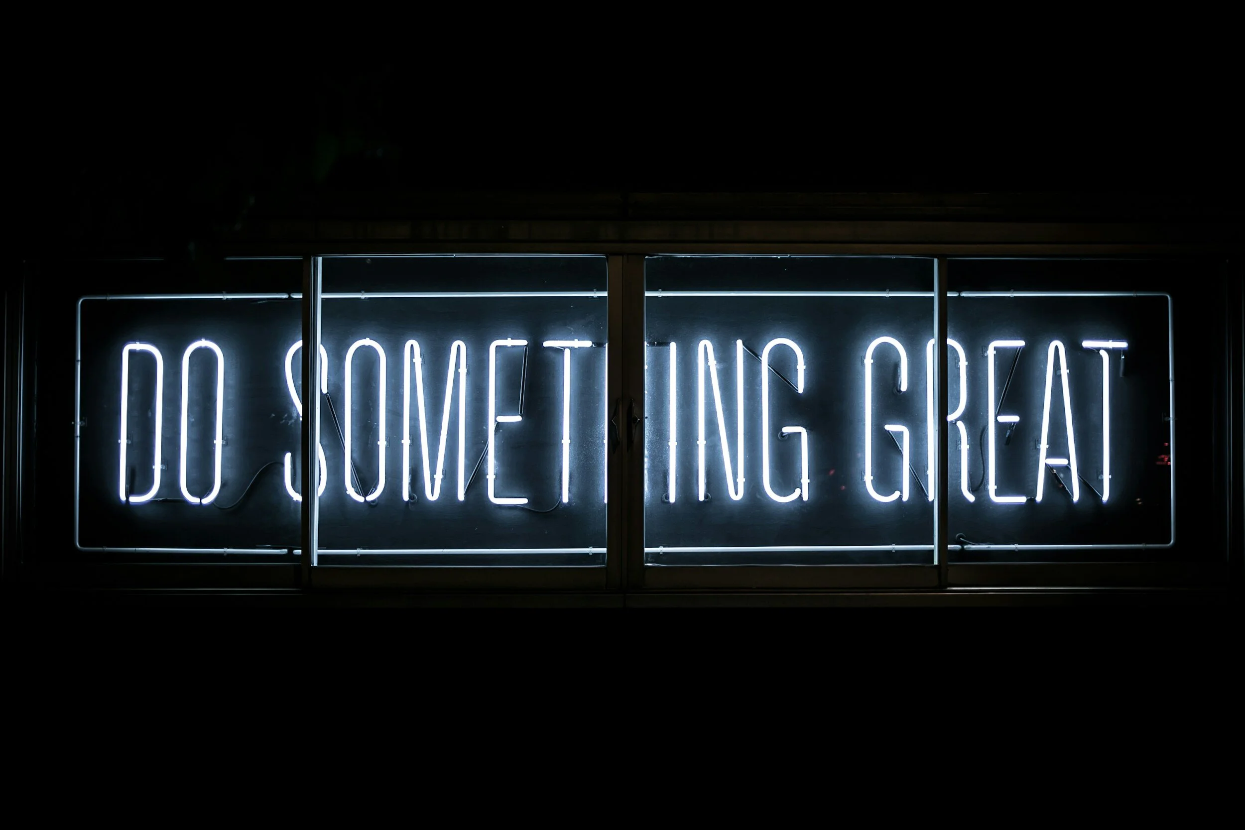 White neon text saying 'Do Something Great' on a black background.