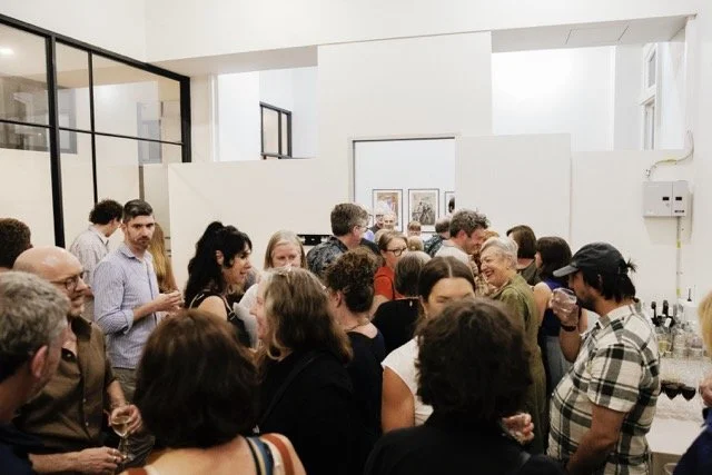Group of people socializing at an indoor event with drinks in hand.