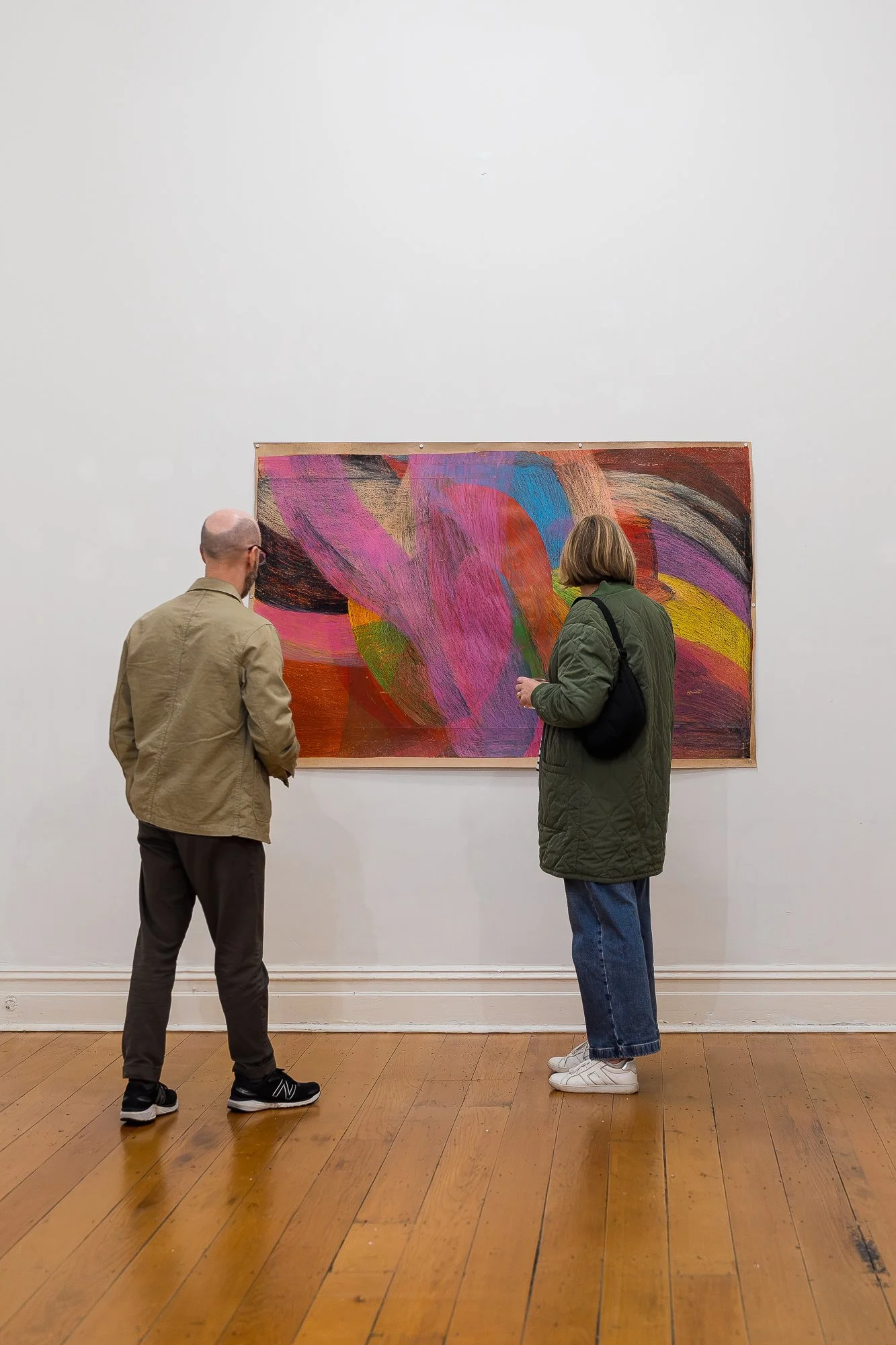 Two people observing a large abstract drawing in an exhibition