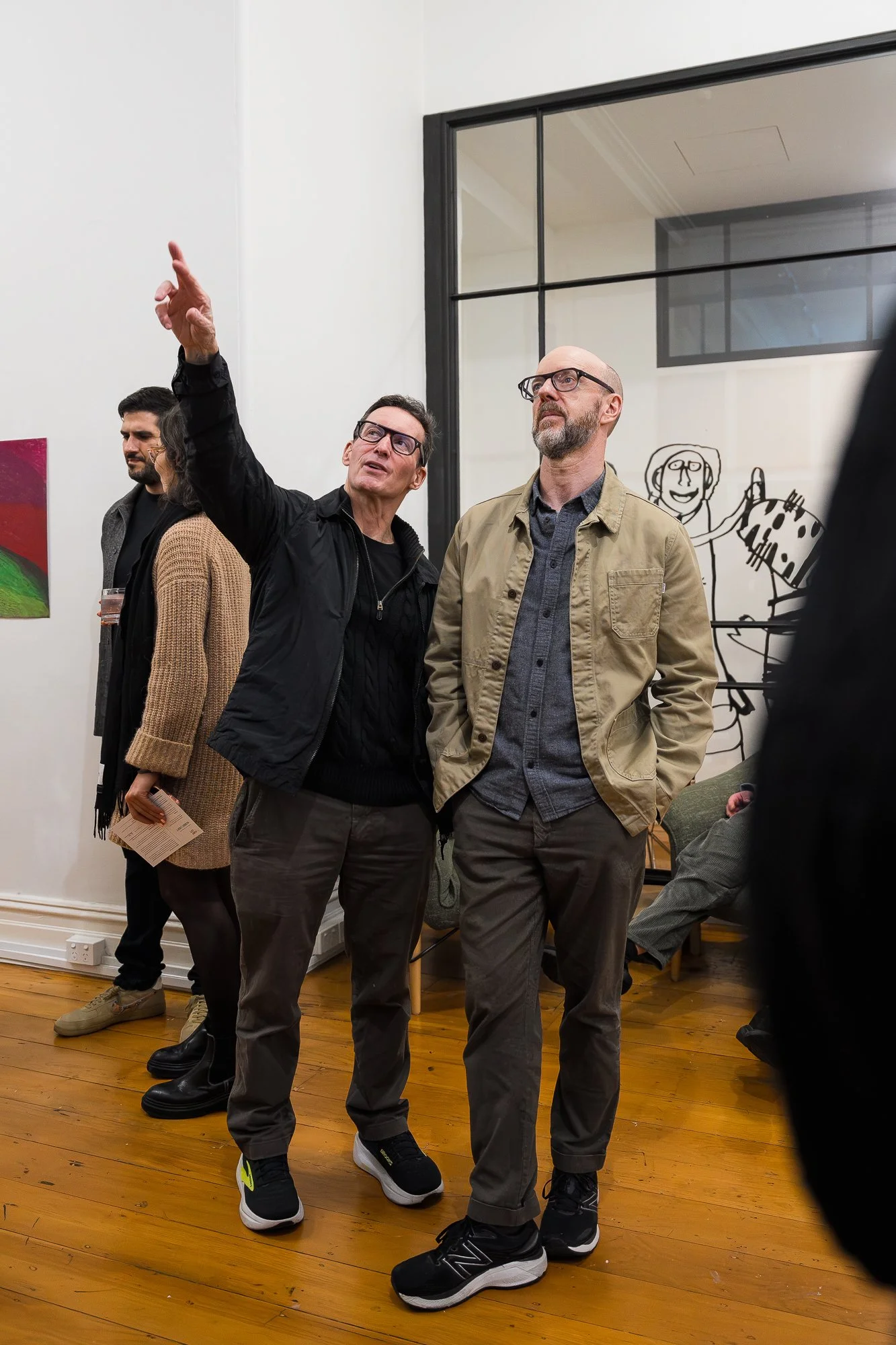 Two people enjoying an exhibition and pointing at artwork