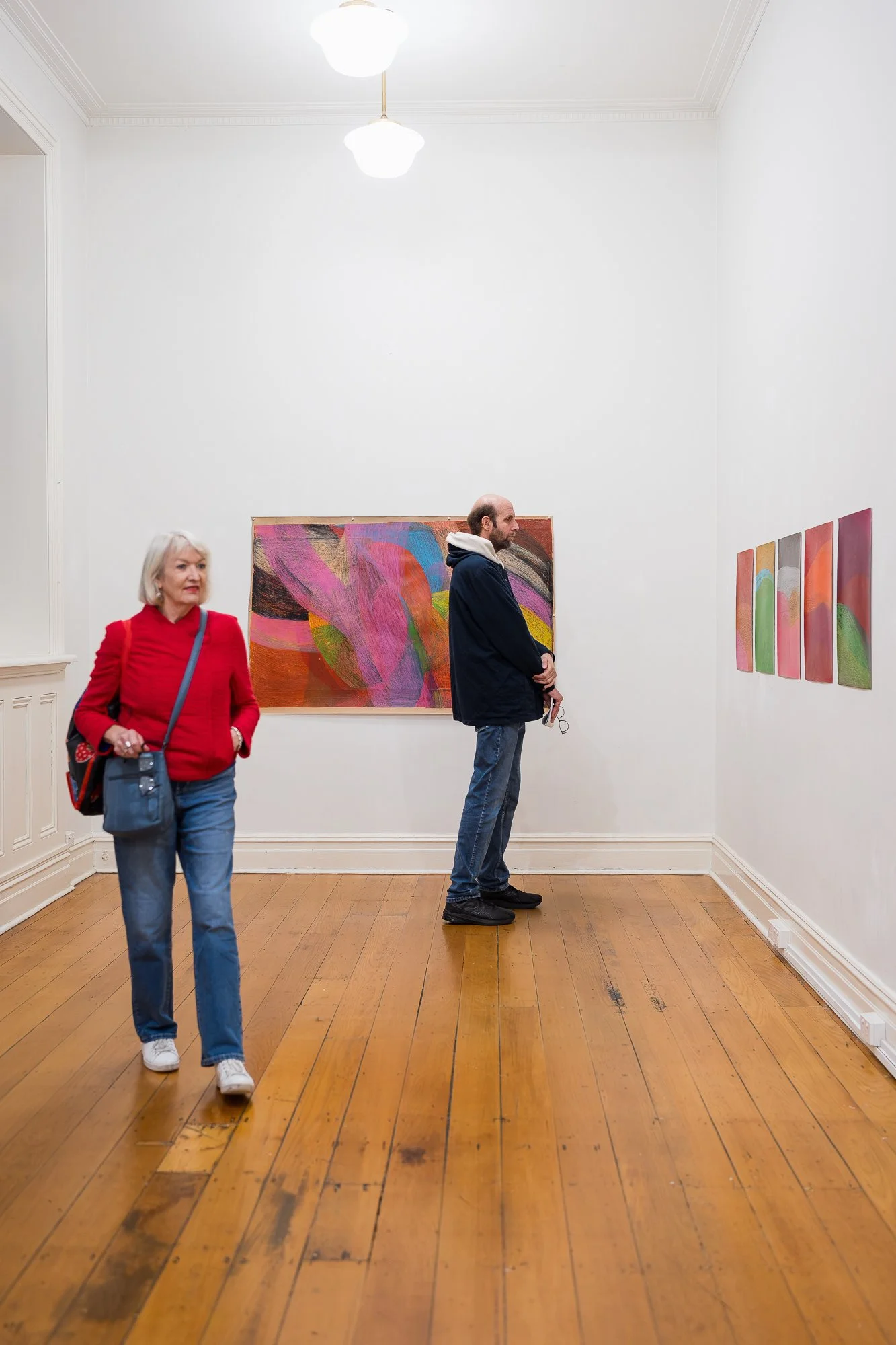 People observing colourful abstract drawingsw at an exhibition