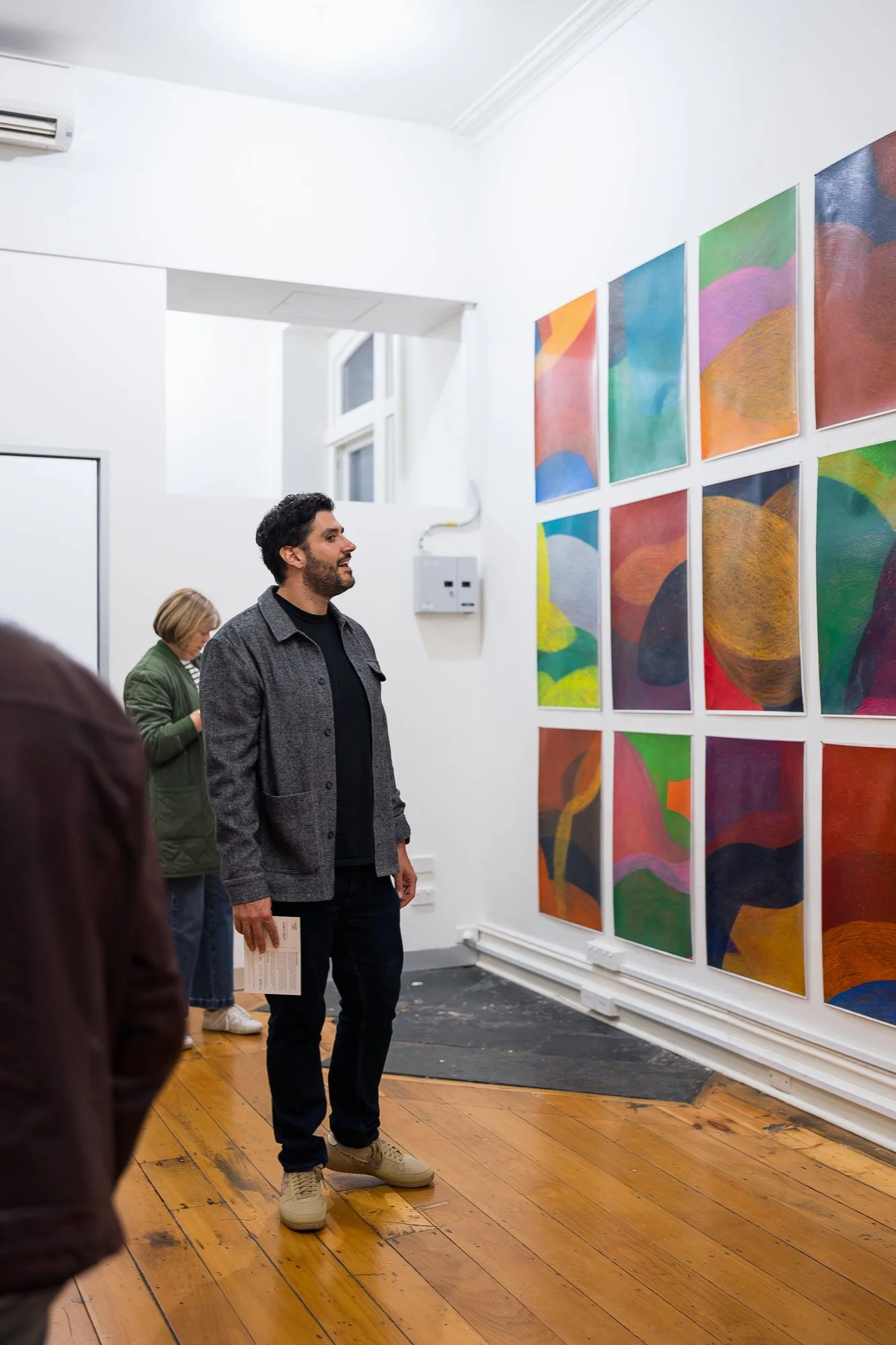 People observing a large abstract drawing installation in an exhibition