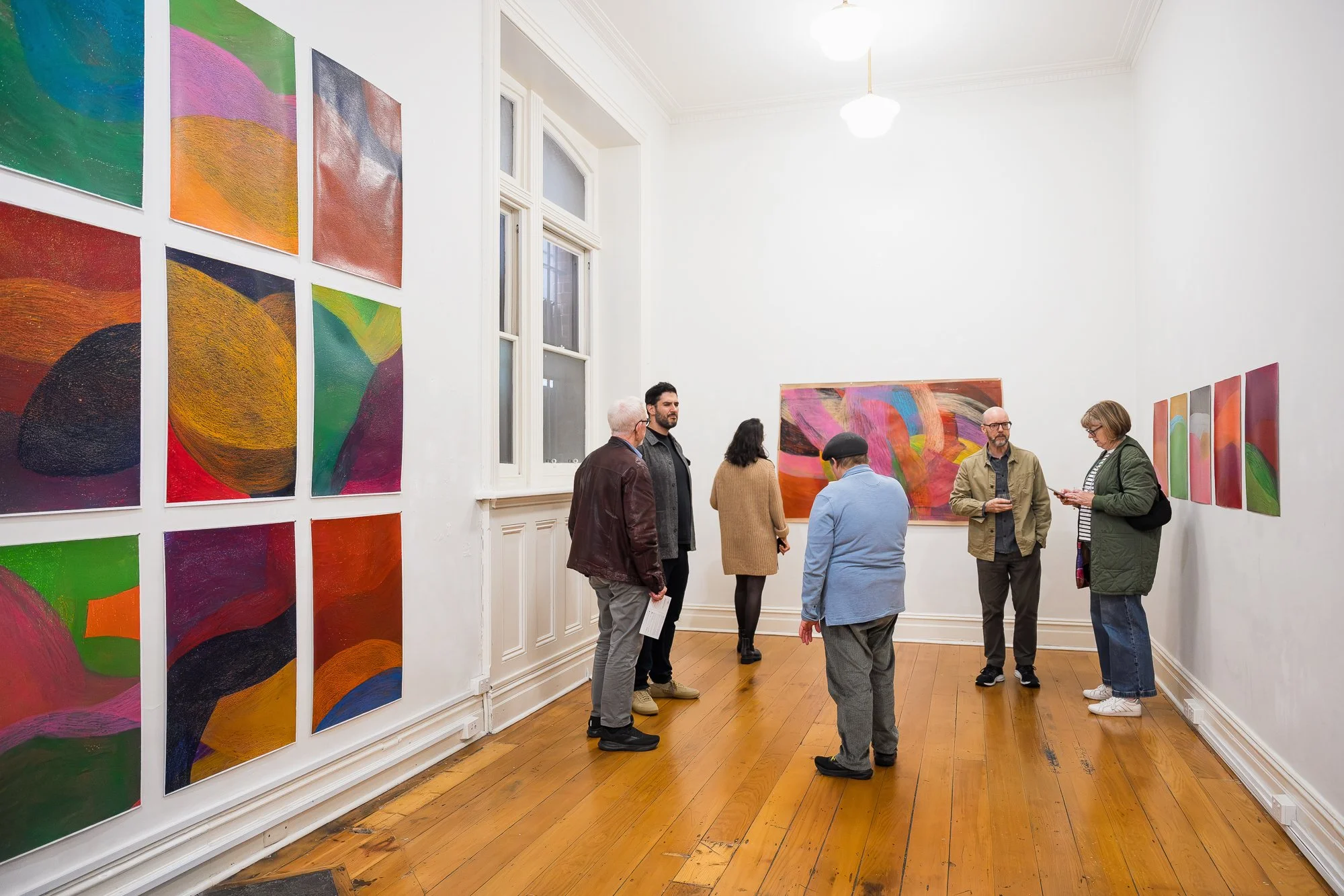 Group of people talking and enjoying colourful drawings at an exhibition