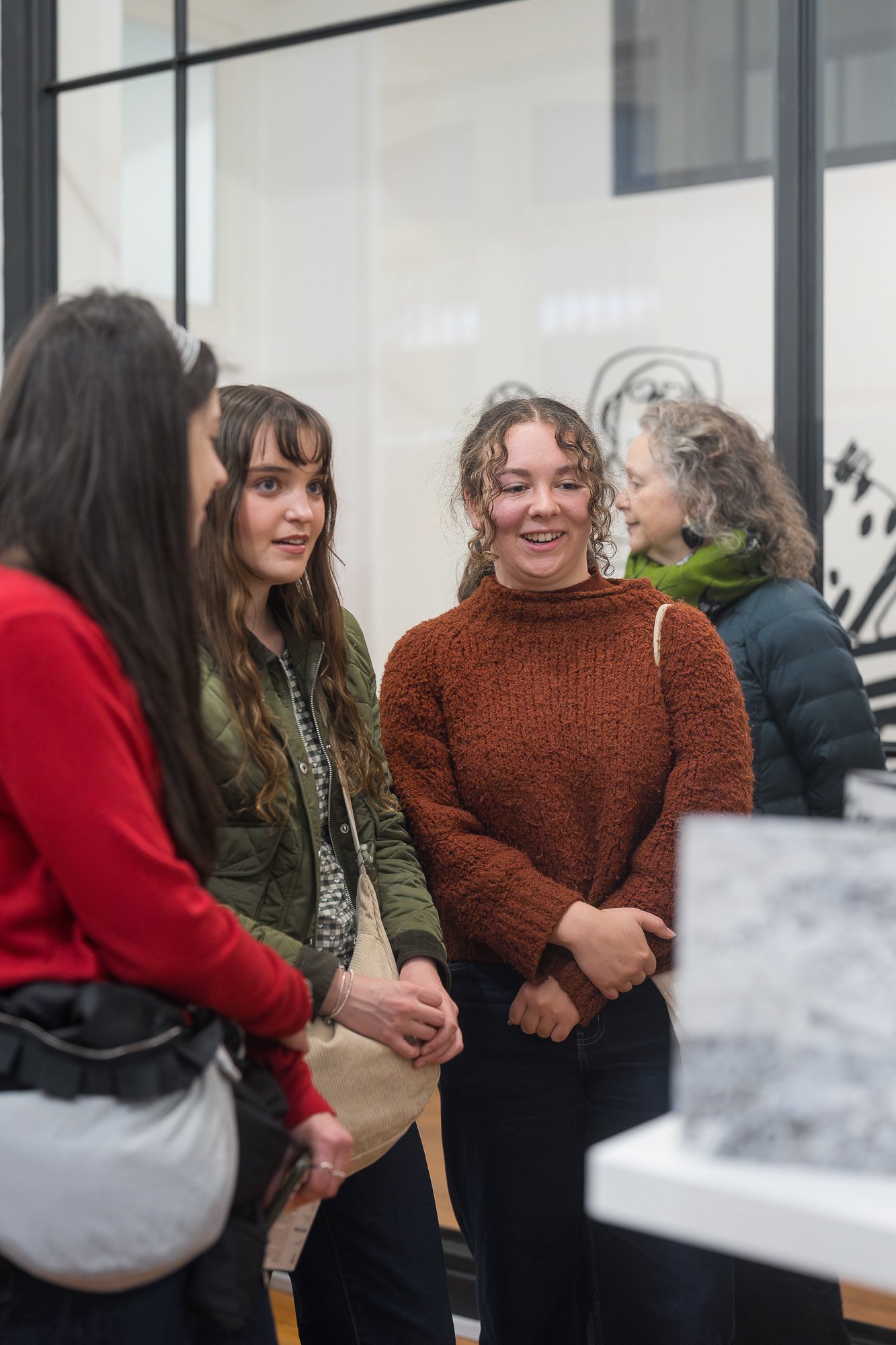A group of young people laugh and talk together at the opening.