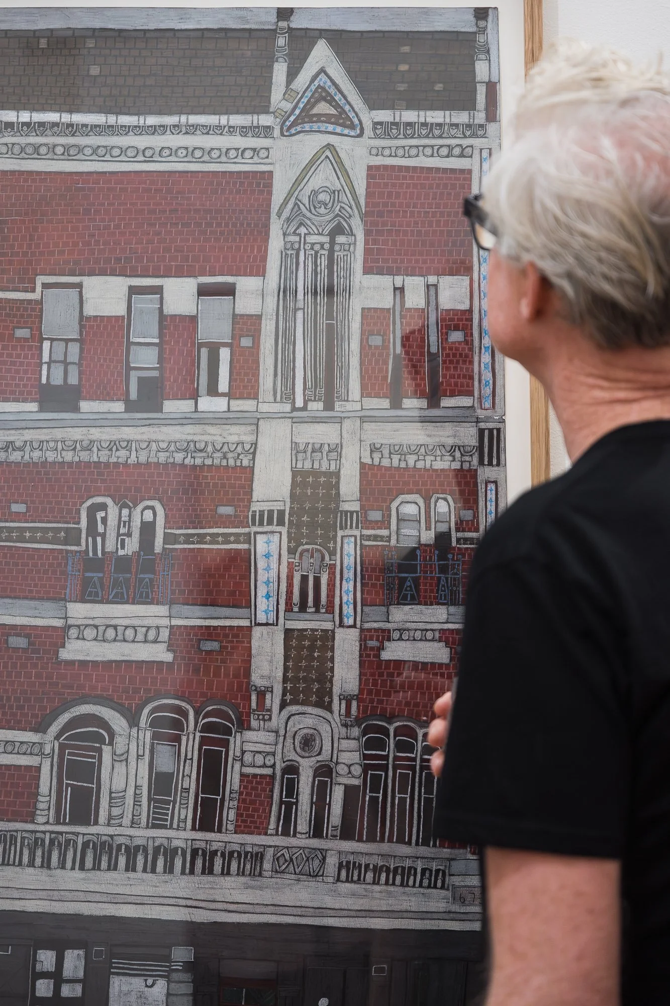 Close-up of a detailed red-brick building illustration with a man's head and shoulder at the edge of frame.