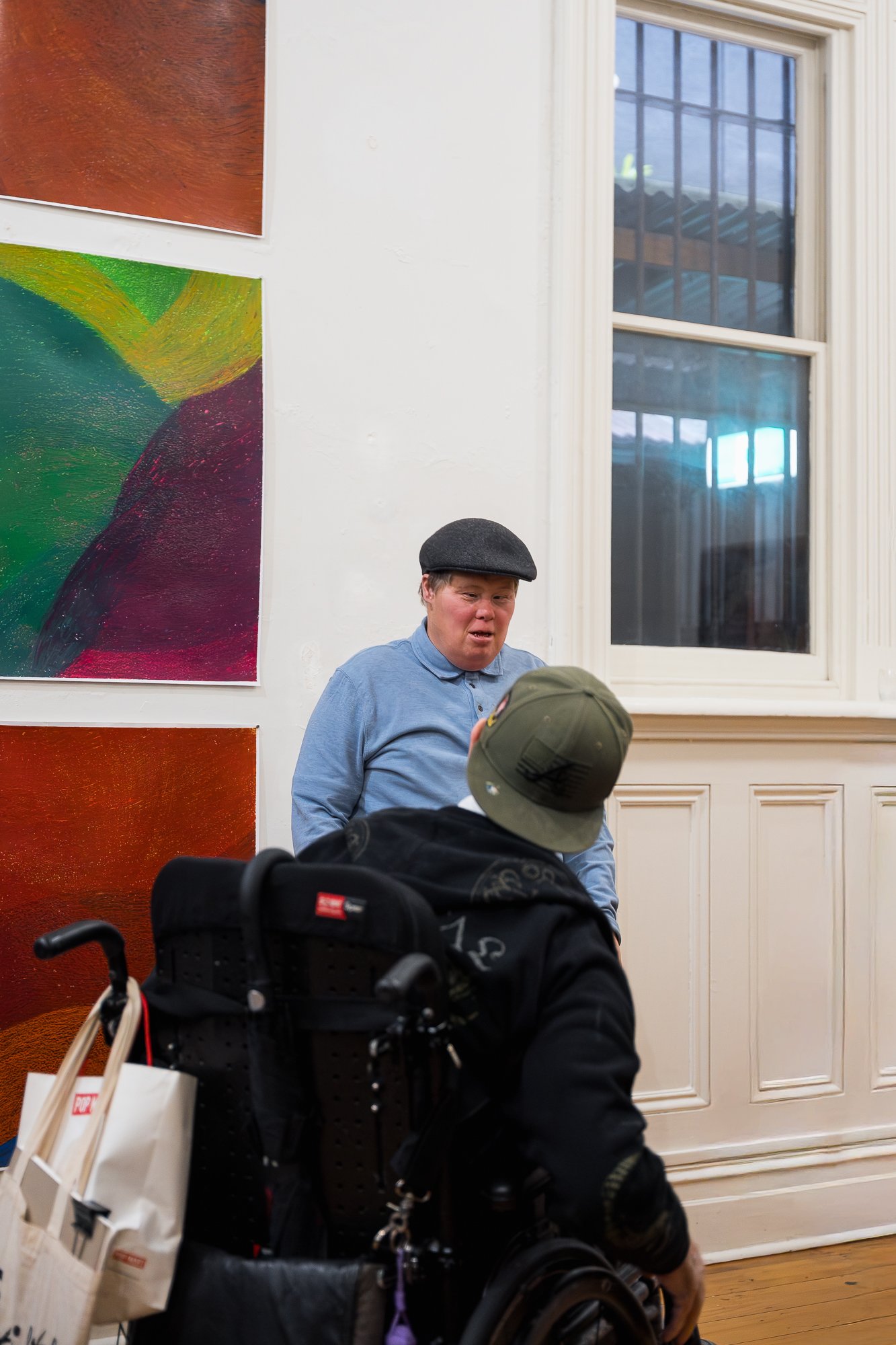 Artist talking to a man in a wheelchair at an exhibition