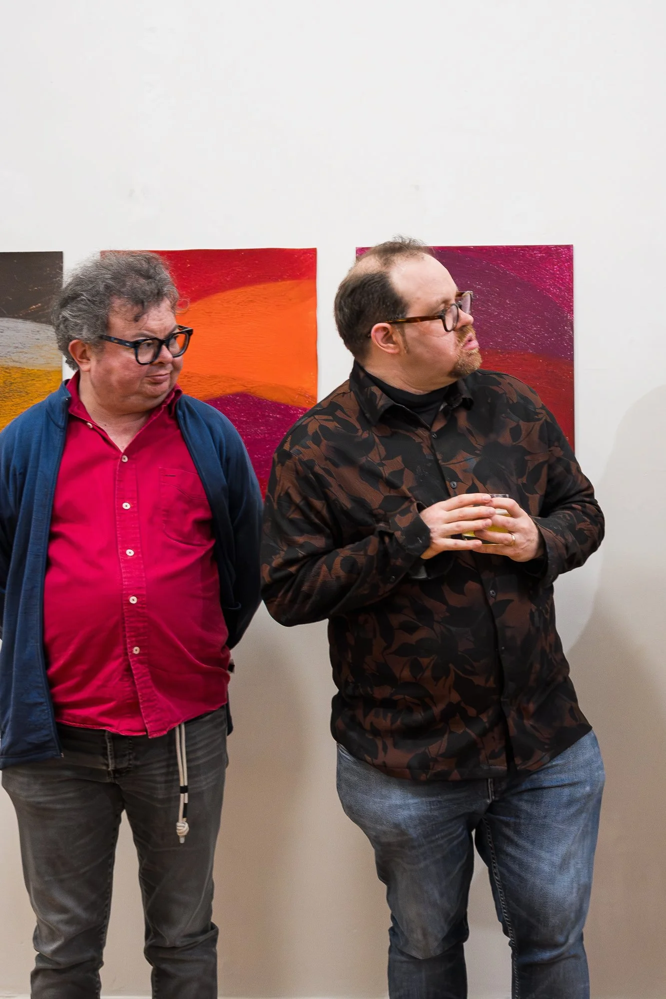 Two people in front of a colourful drawing at an exhibition