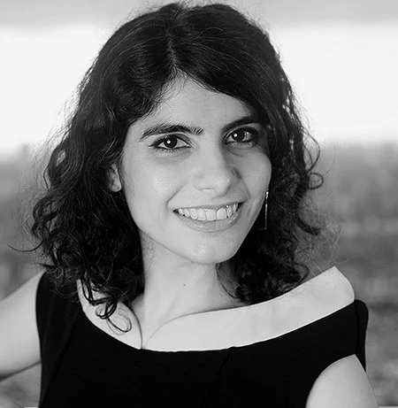 Smiling person with curly hair in a black and white photo.
