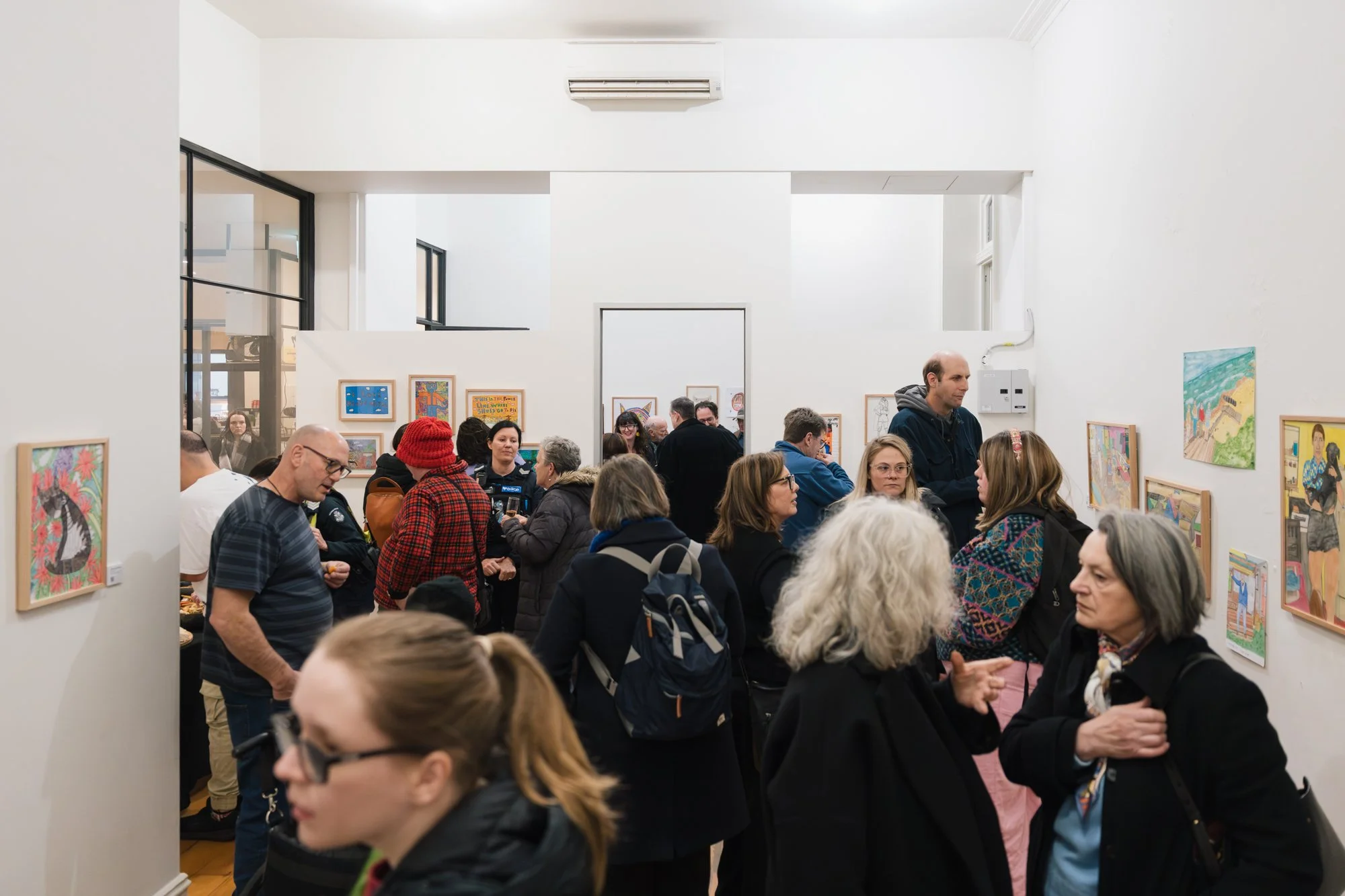 Opening of Convergence 2025 with many people in a light filled gallery space.