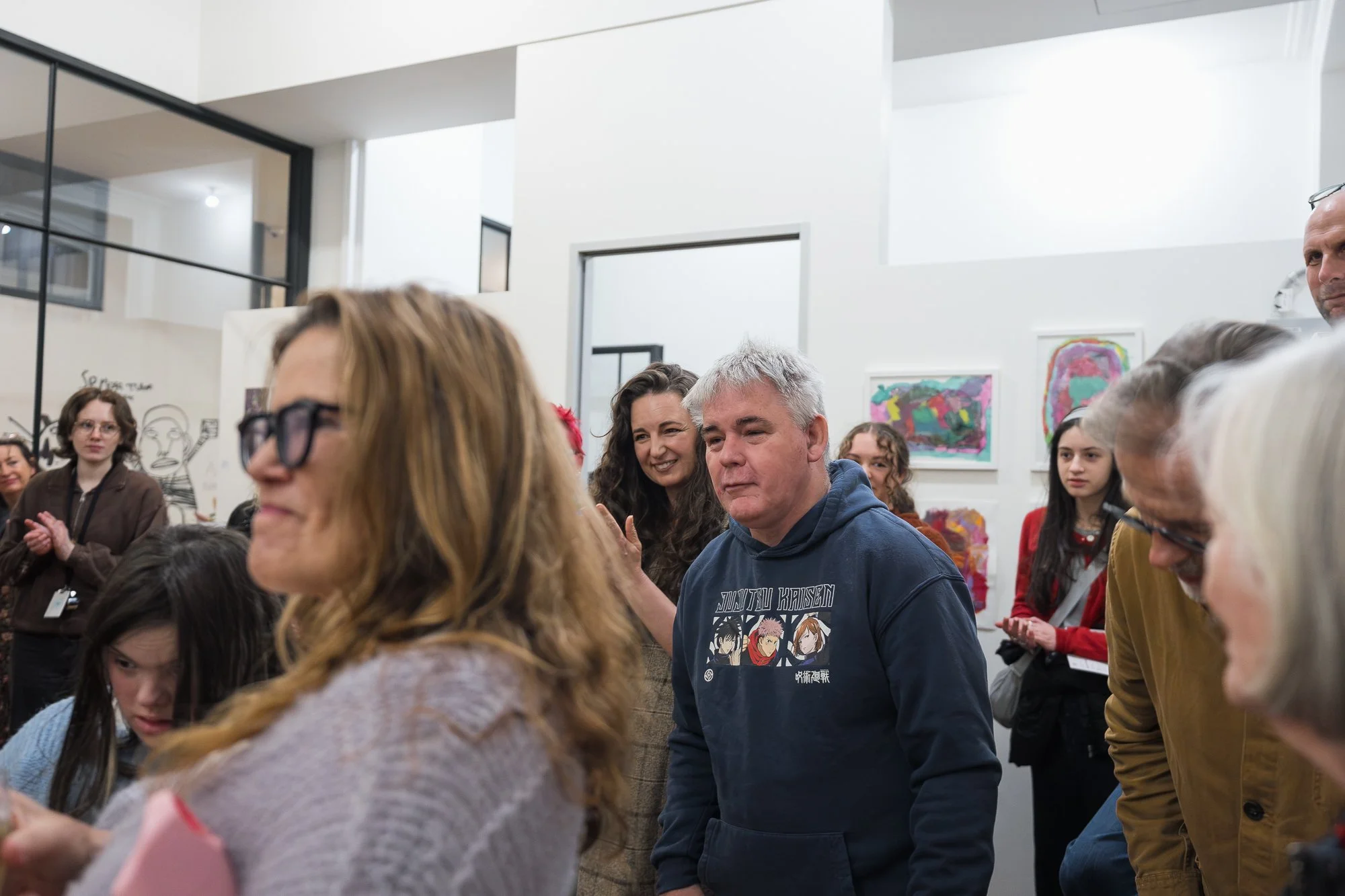 An artist is acknowledged by the crowd — a warm, applauding room, faces smiling in every direction.