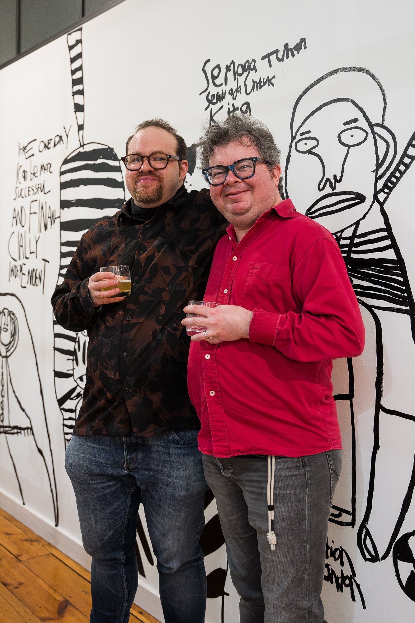 Two people smiling happily at an exhibition opening