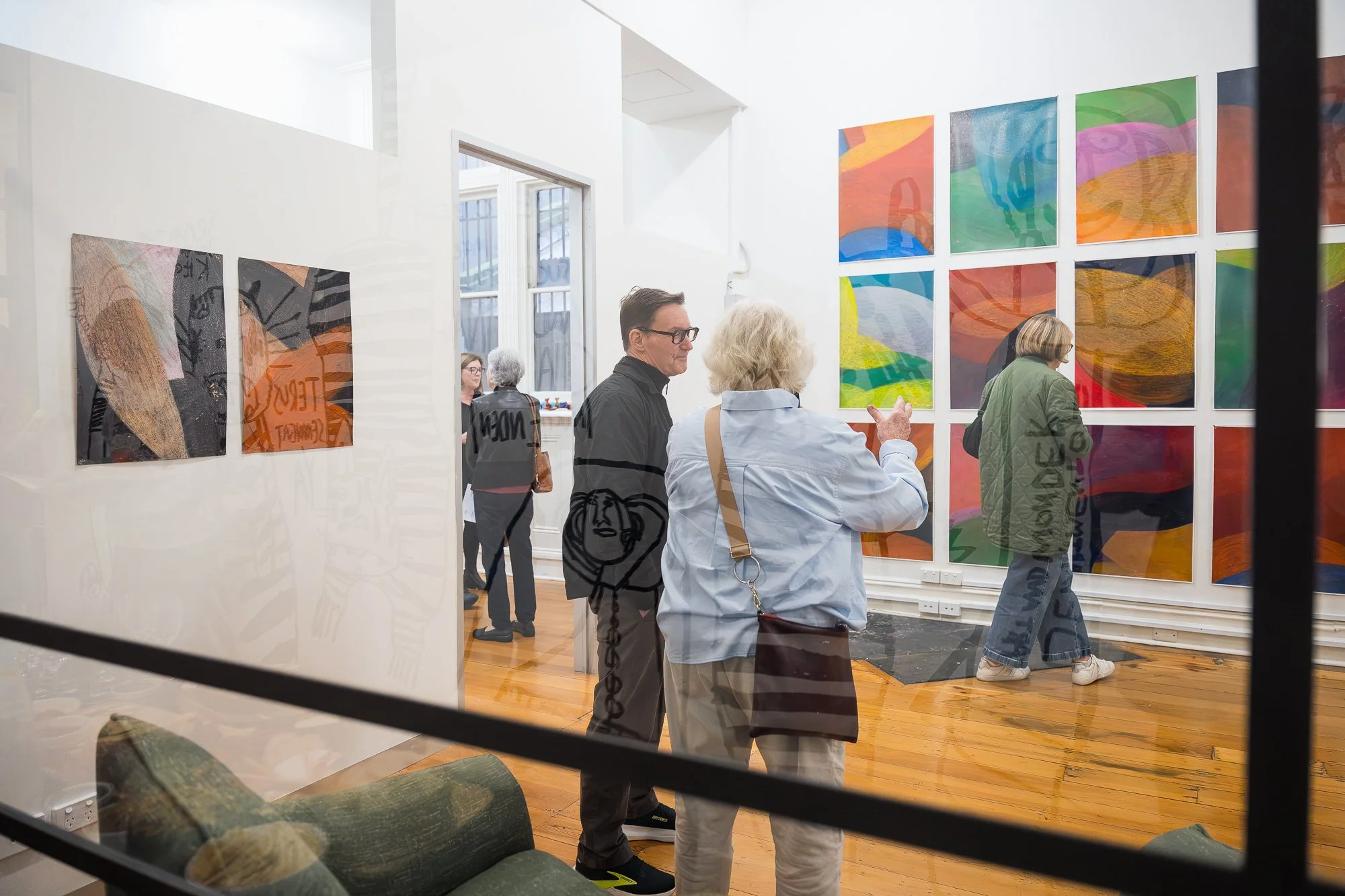 People observing a large abstract drawing installation in an exhibition